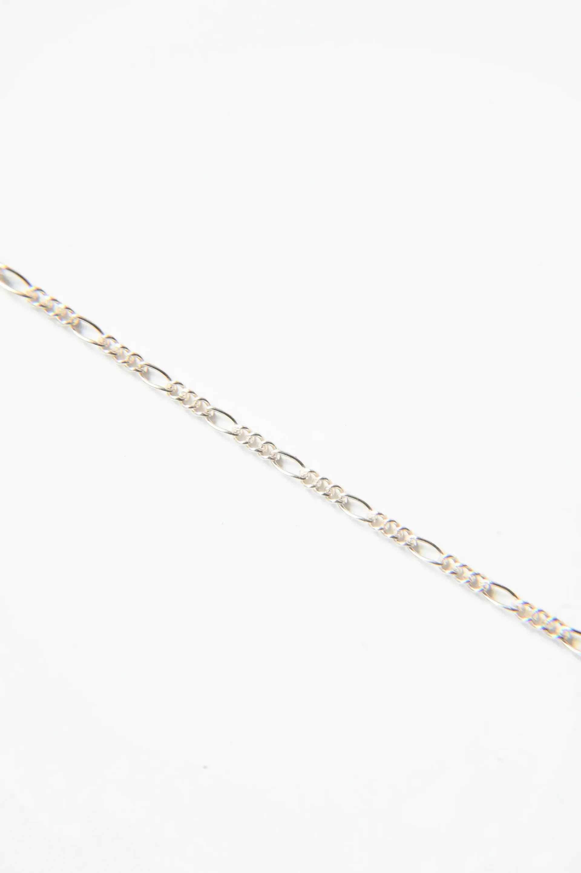 A close up of a gold chain on a white background.