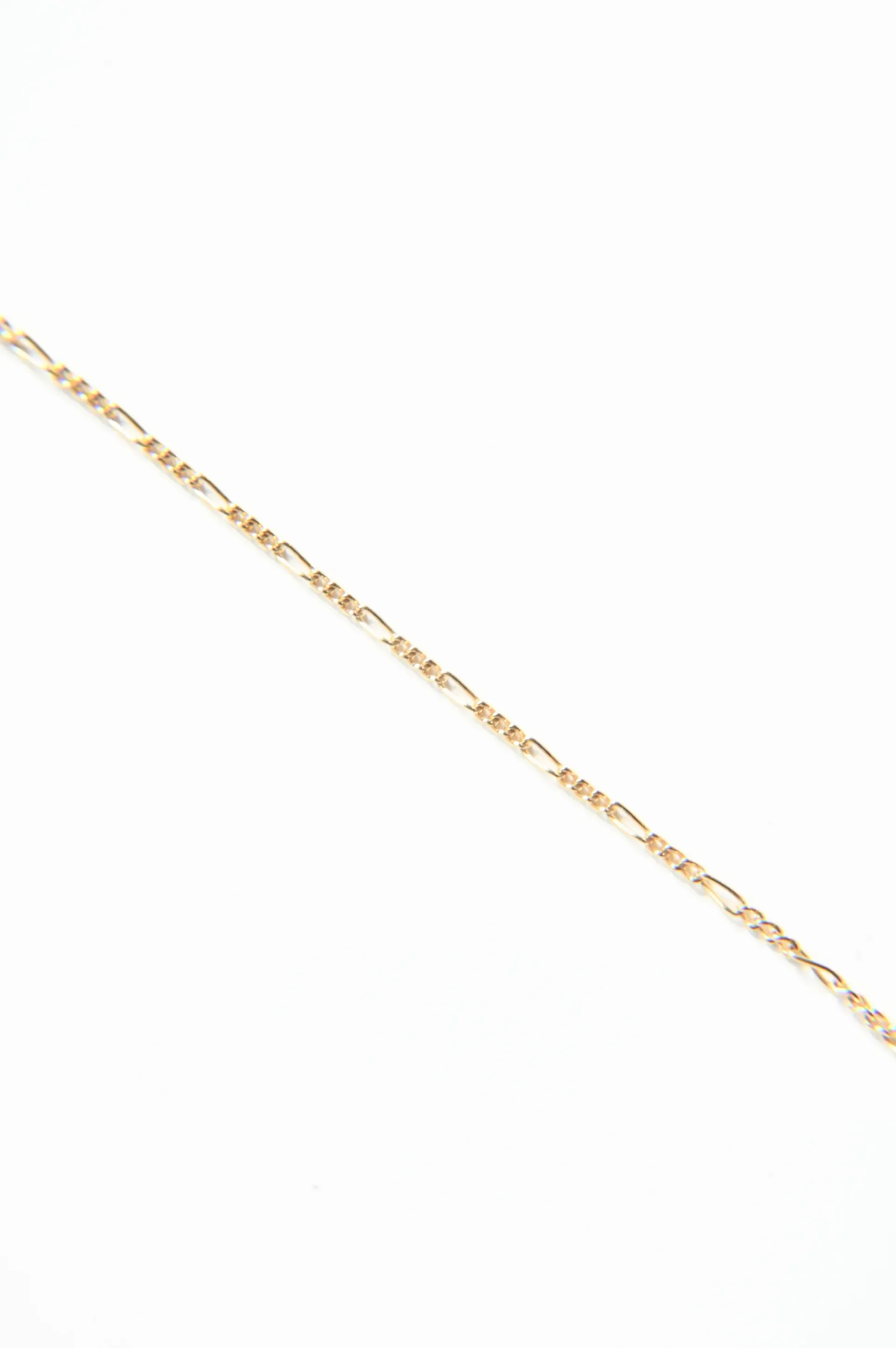A close up of a gold chain on a white background.