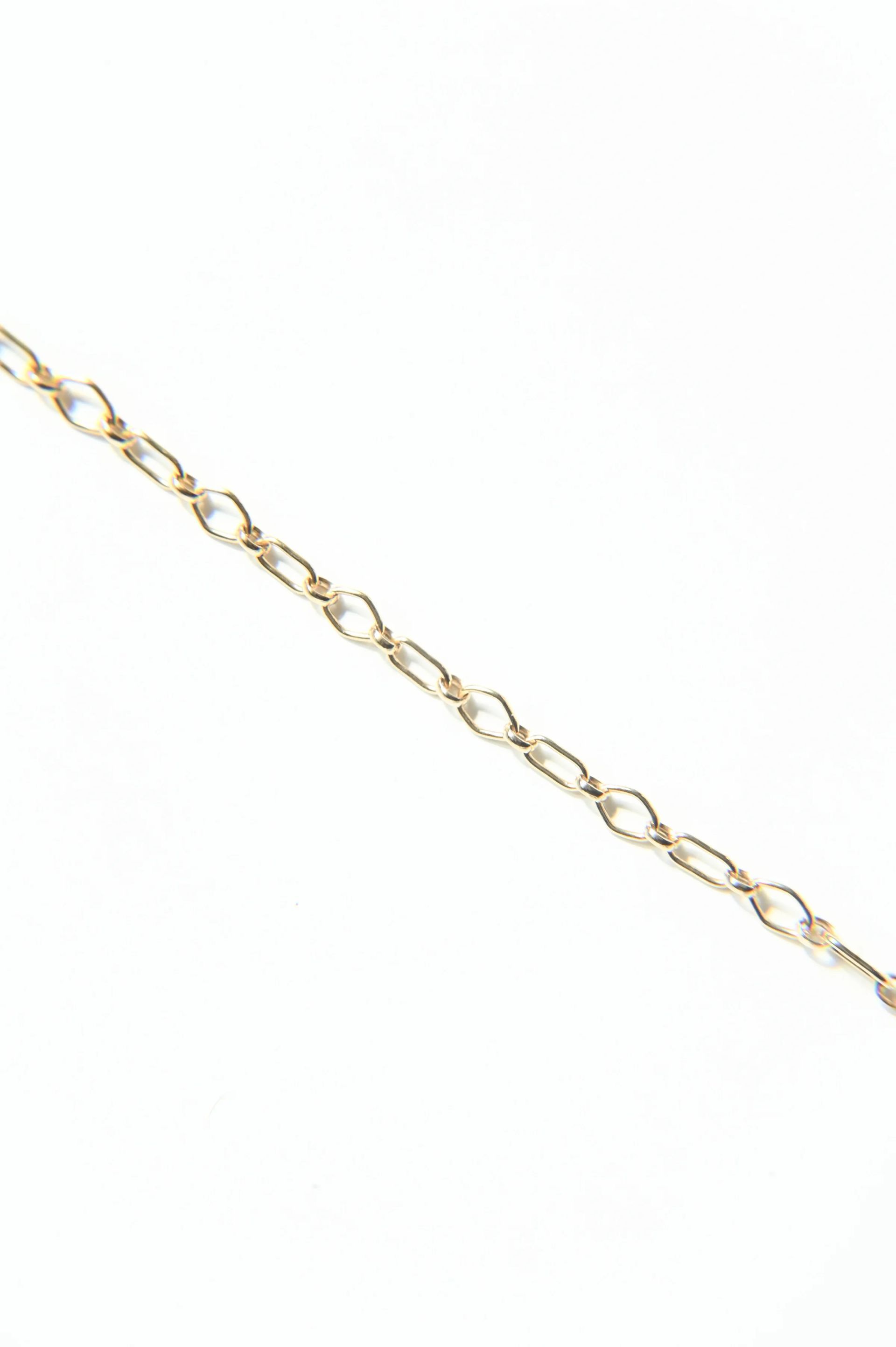 A close up of a gold chain on a white background.