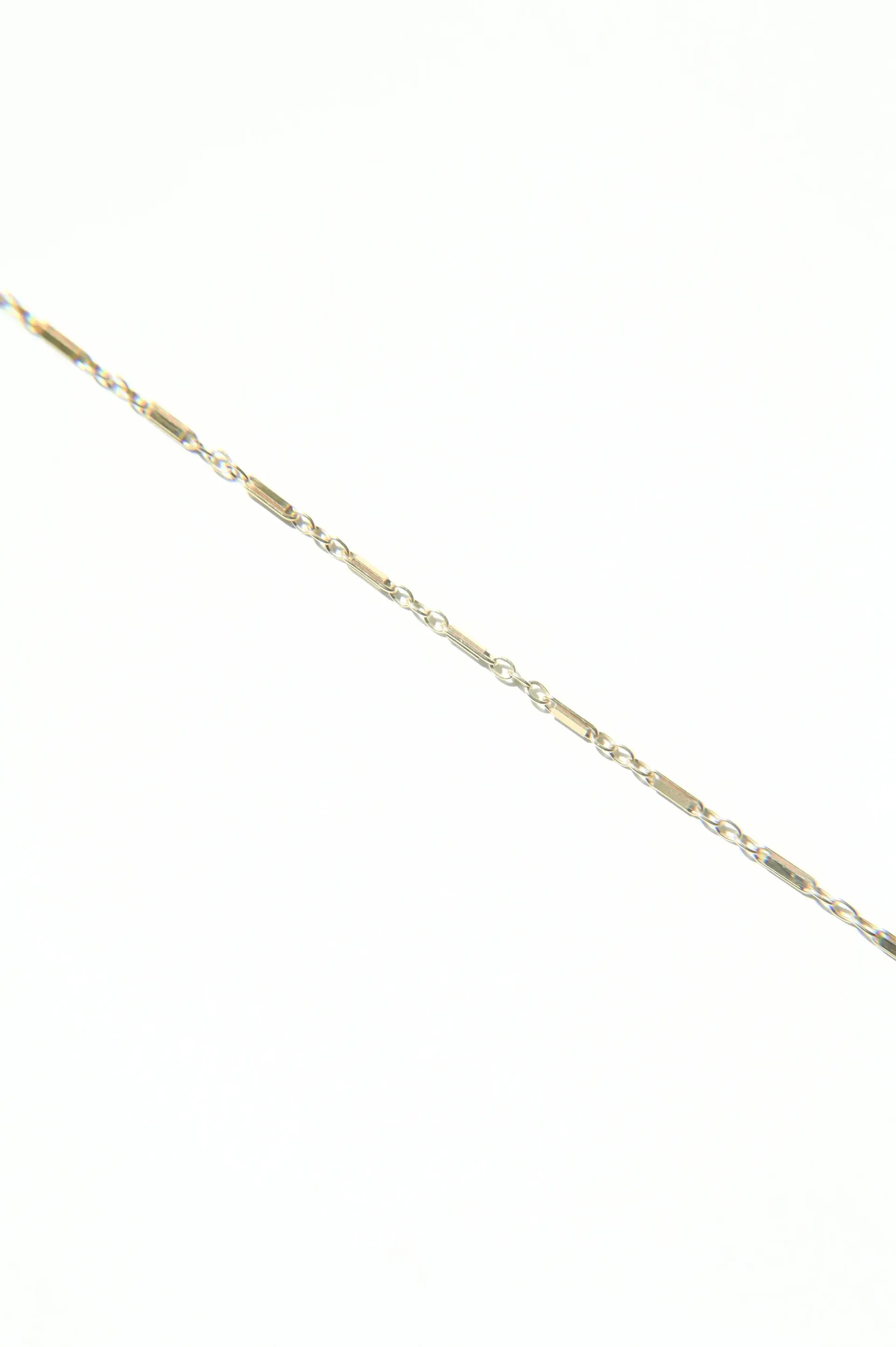 A close up of a gold chain on a white background.