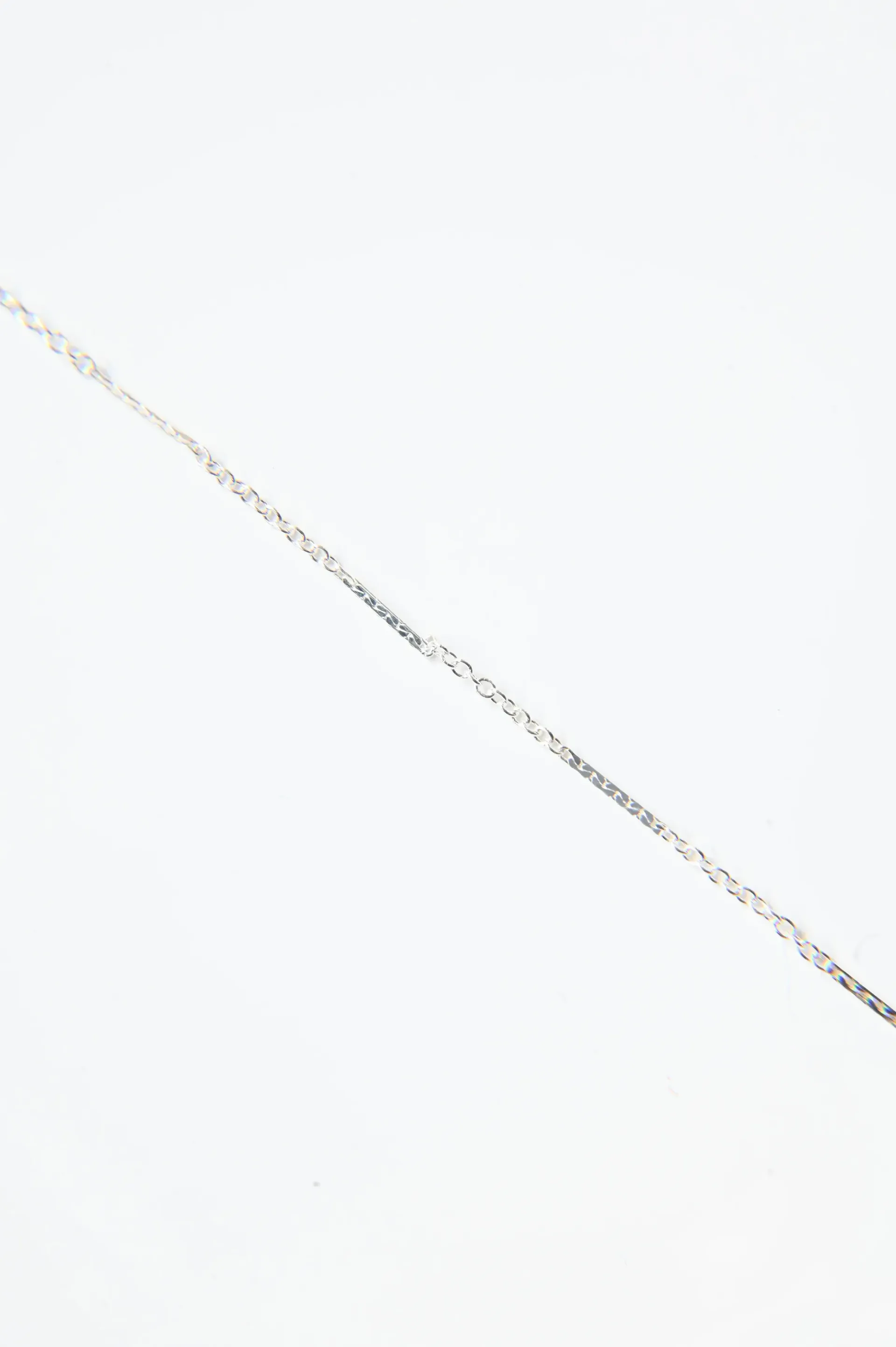 A close up of a silver chain on a white background.