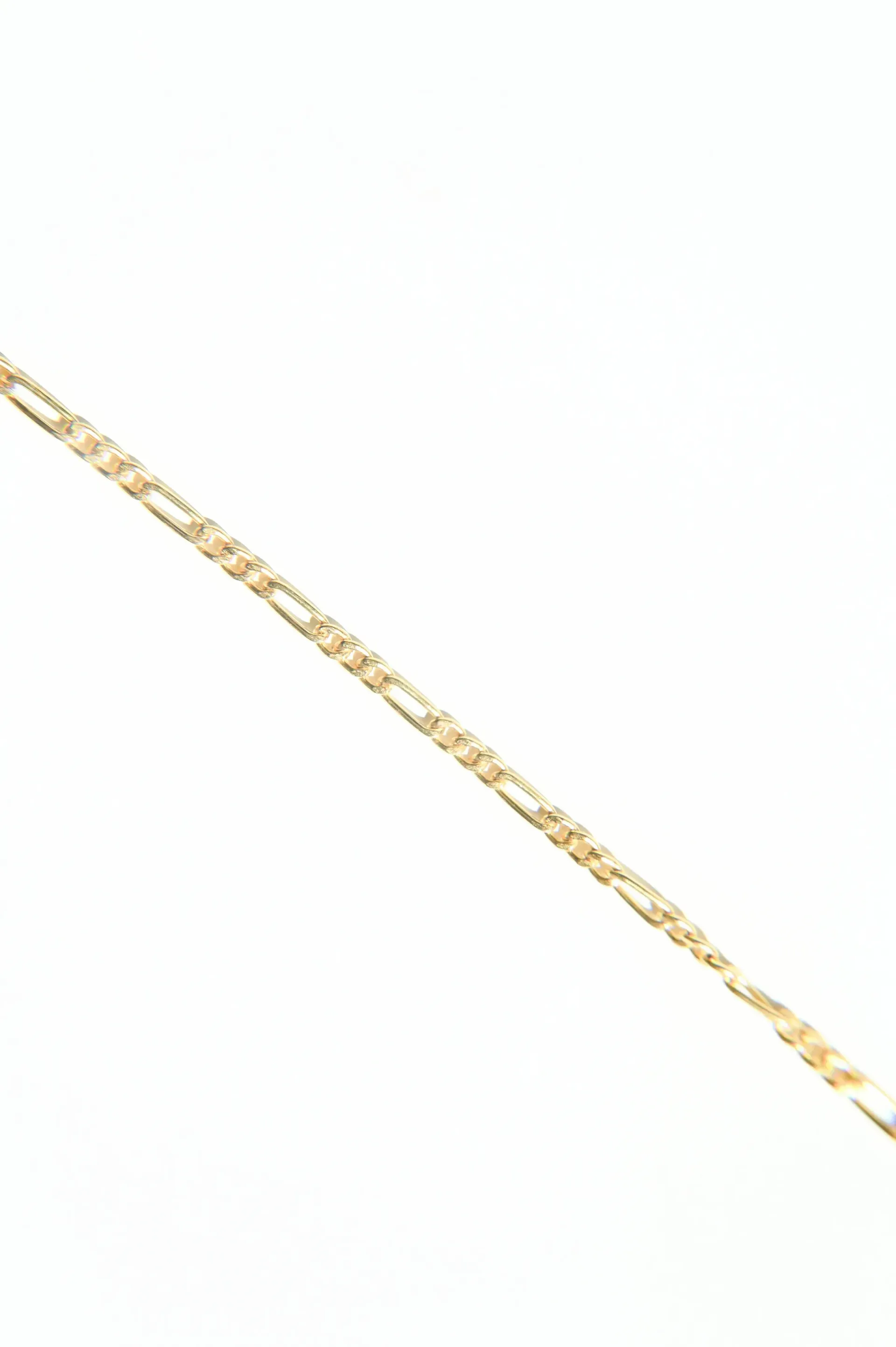 A close up of a gold chain on a white background.