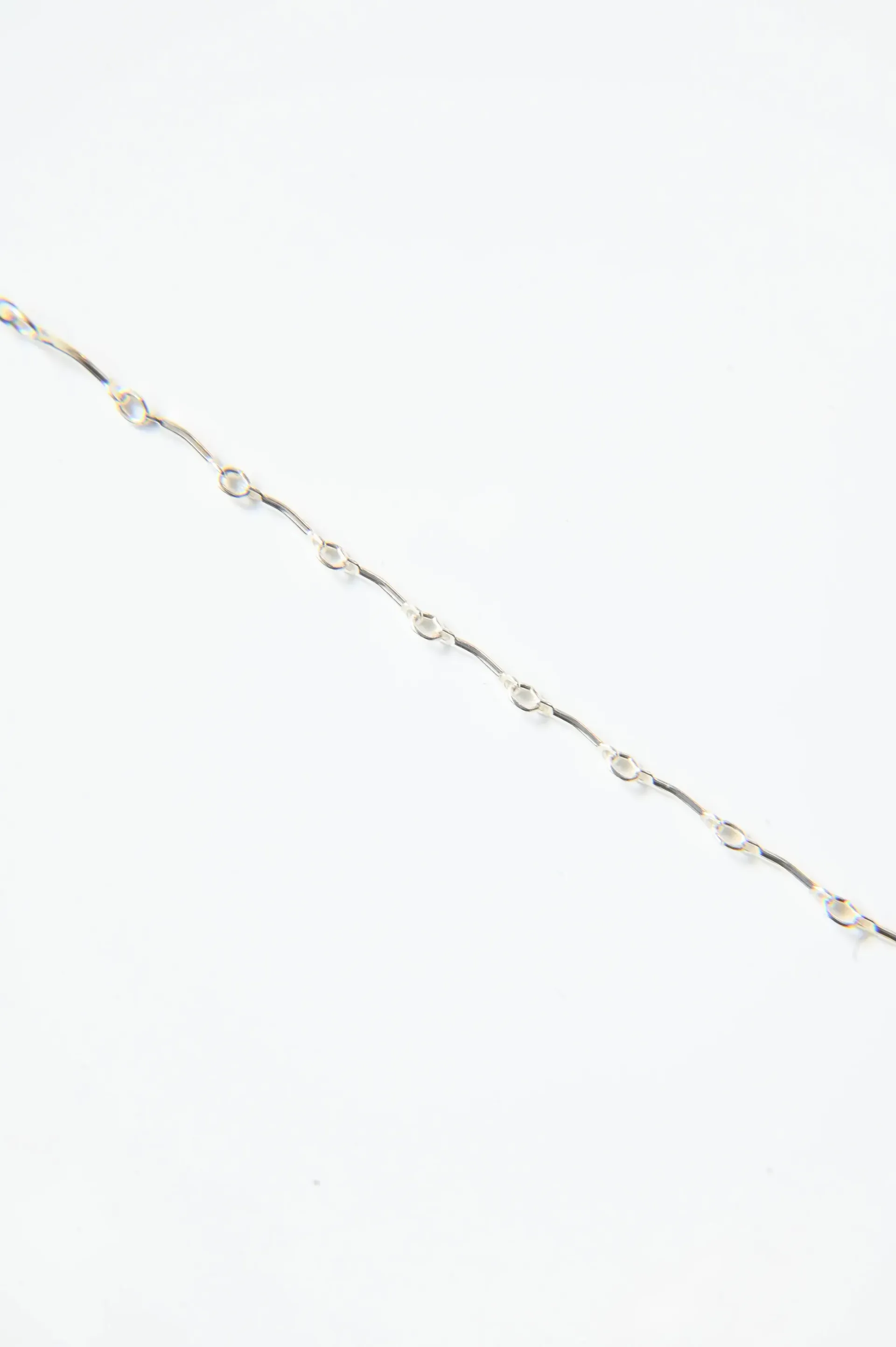 A close up of a silver chain on a white background.