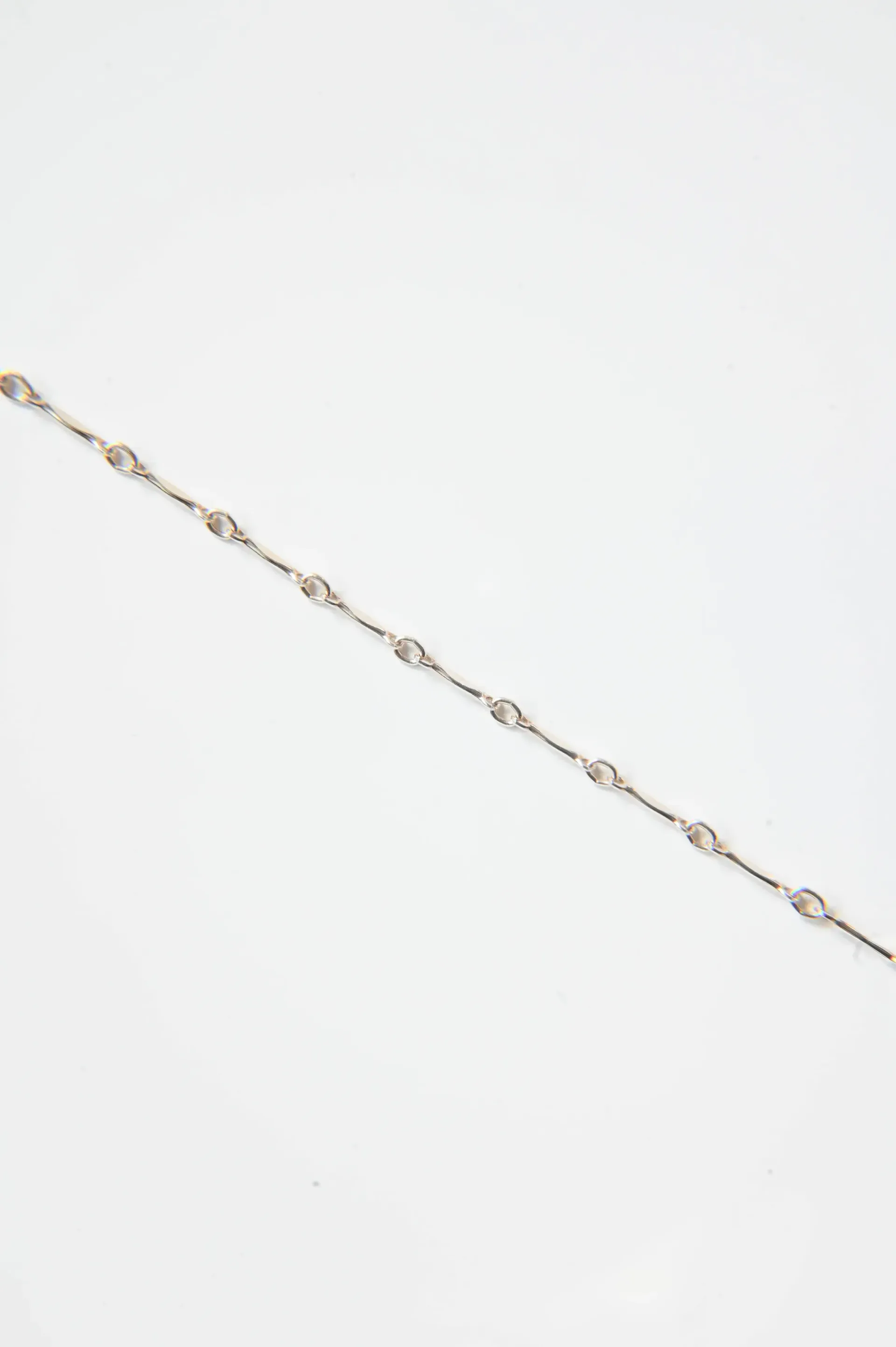 A close up of a bracelet on a white surface.