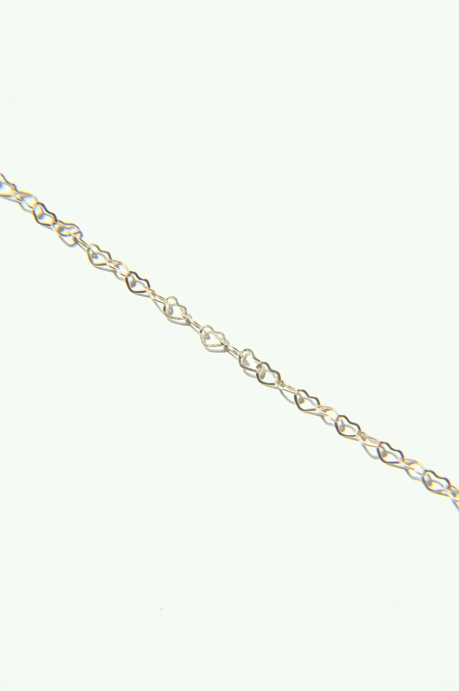 A close up of a gold chain on a white background.