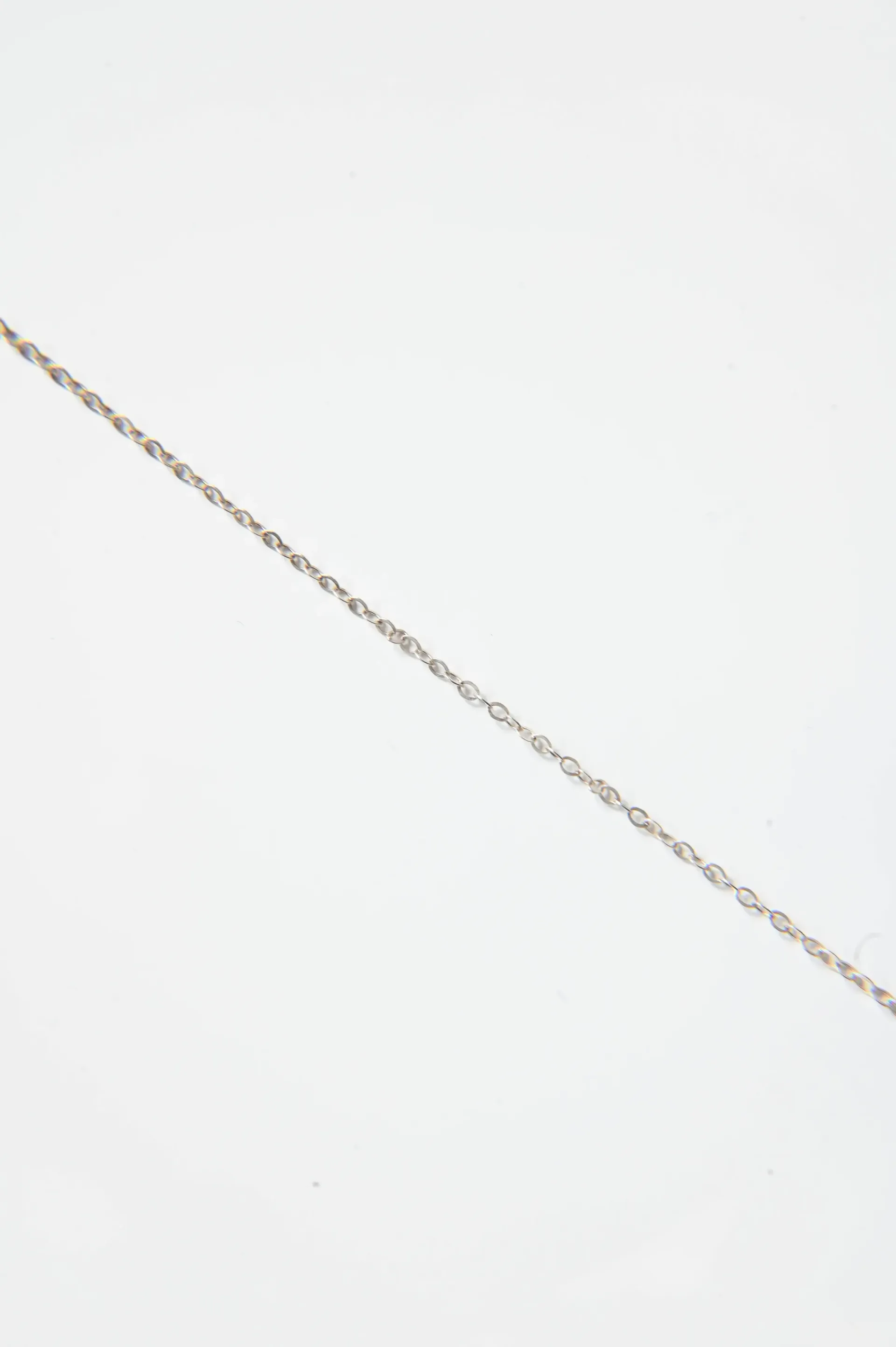 A close up of a silver chain on a white surface.