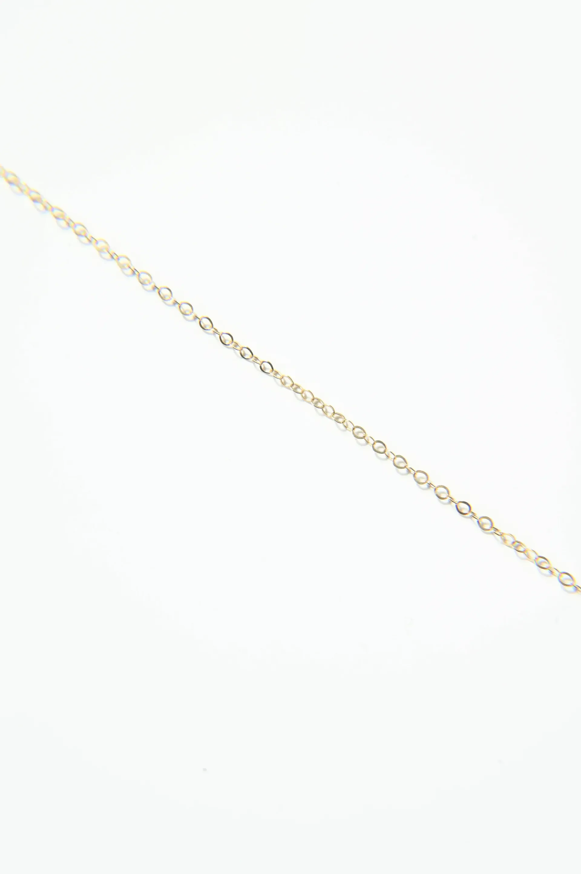 A close up of a gold chain on a white background.
