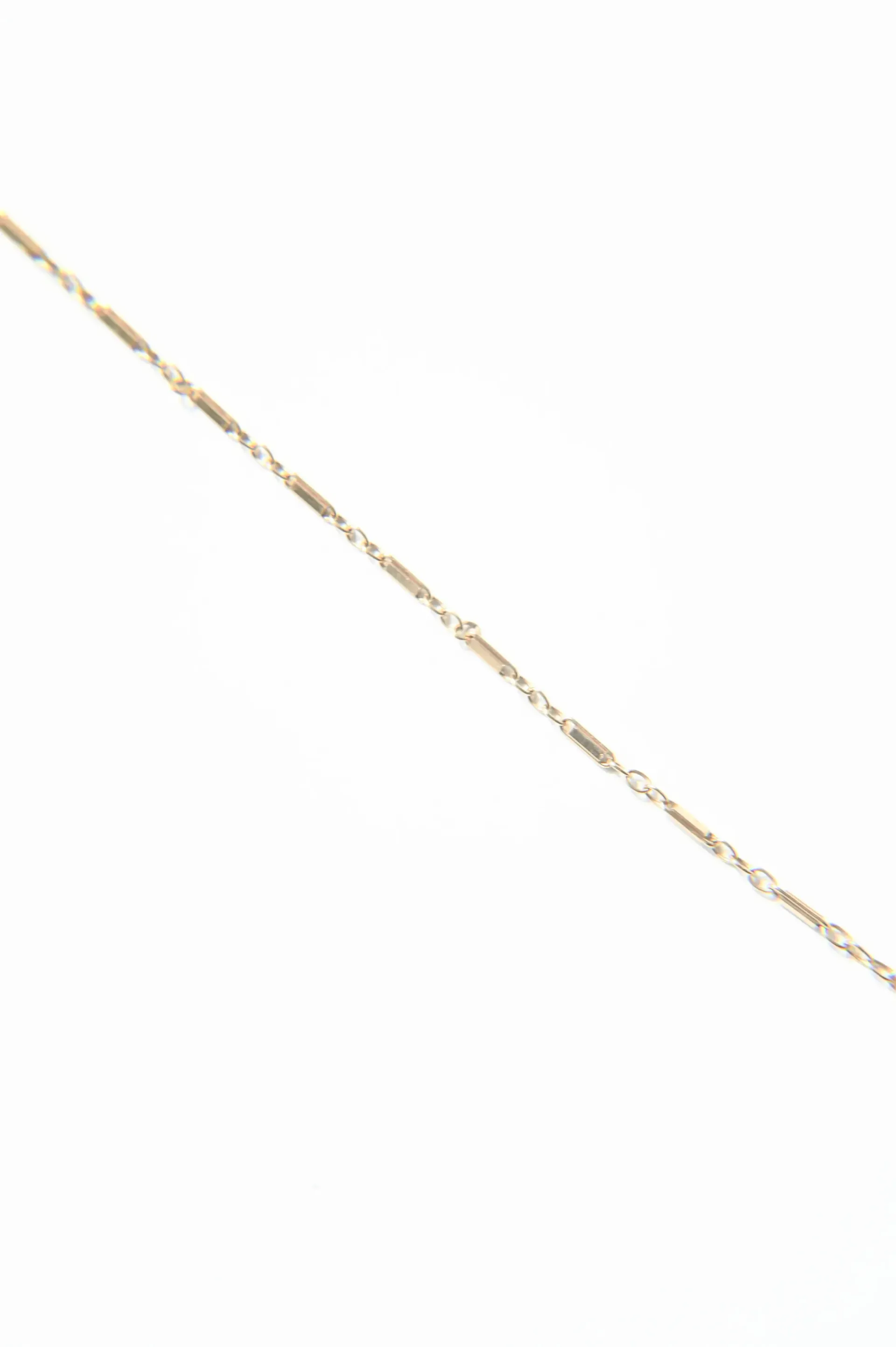 A close up of a gold chain on a white background.