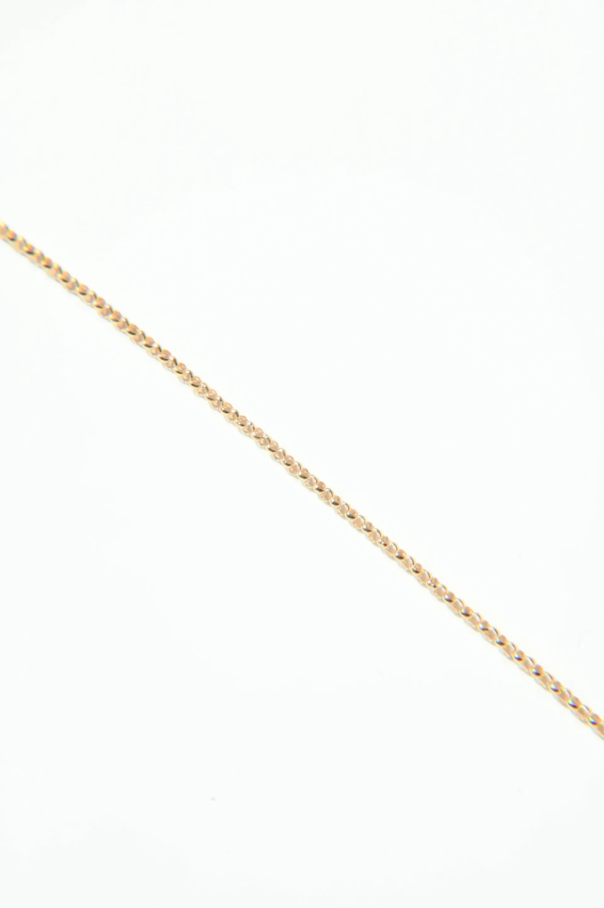 A close up of a gold chain on a white background.