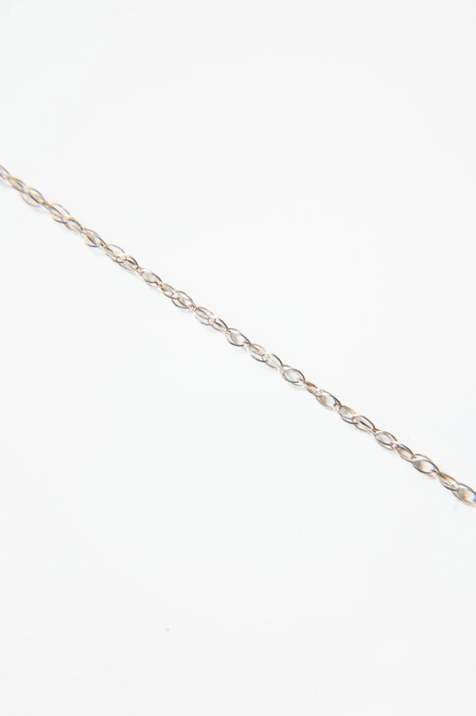 A close up of a silver chain on a white background.