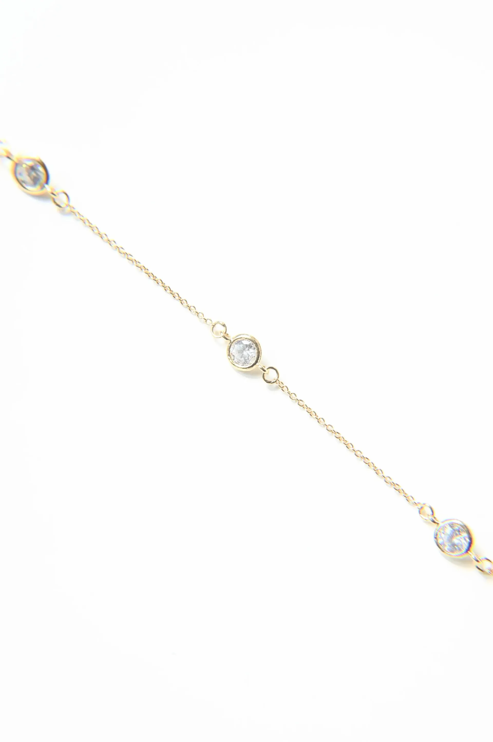 A gold bracelet with three diamonds on a chain on a white background.