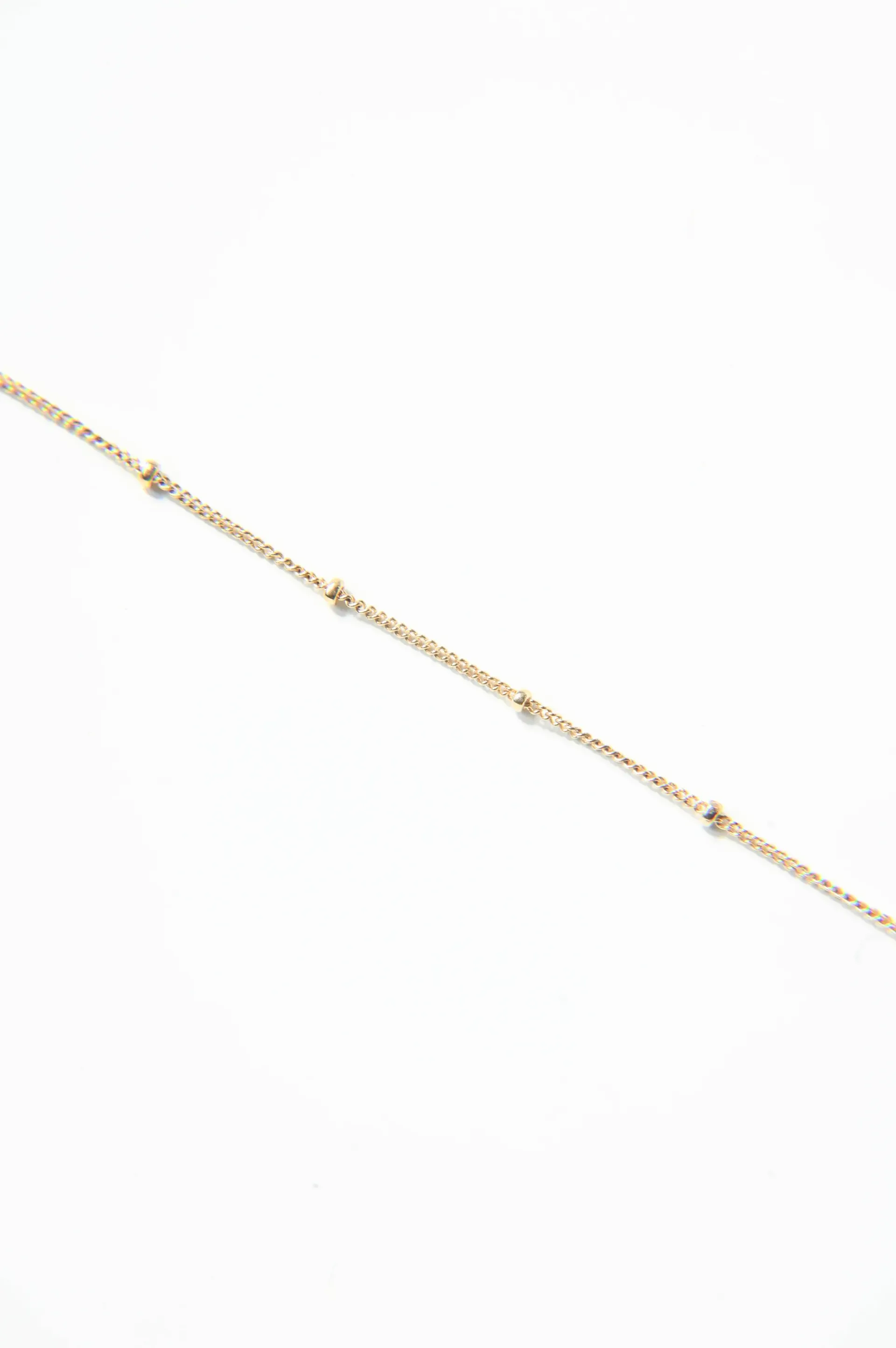 A close up of a gold chain on a white background.