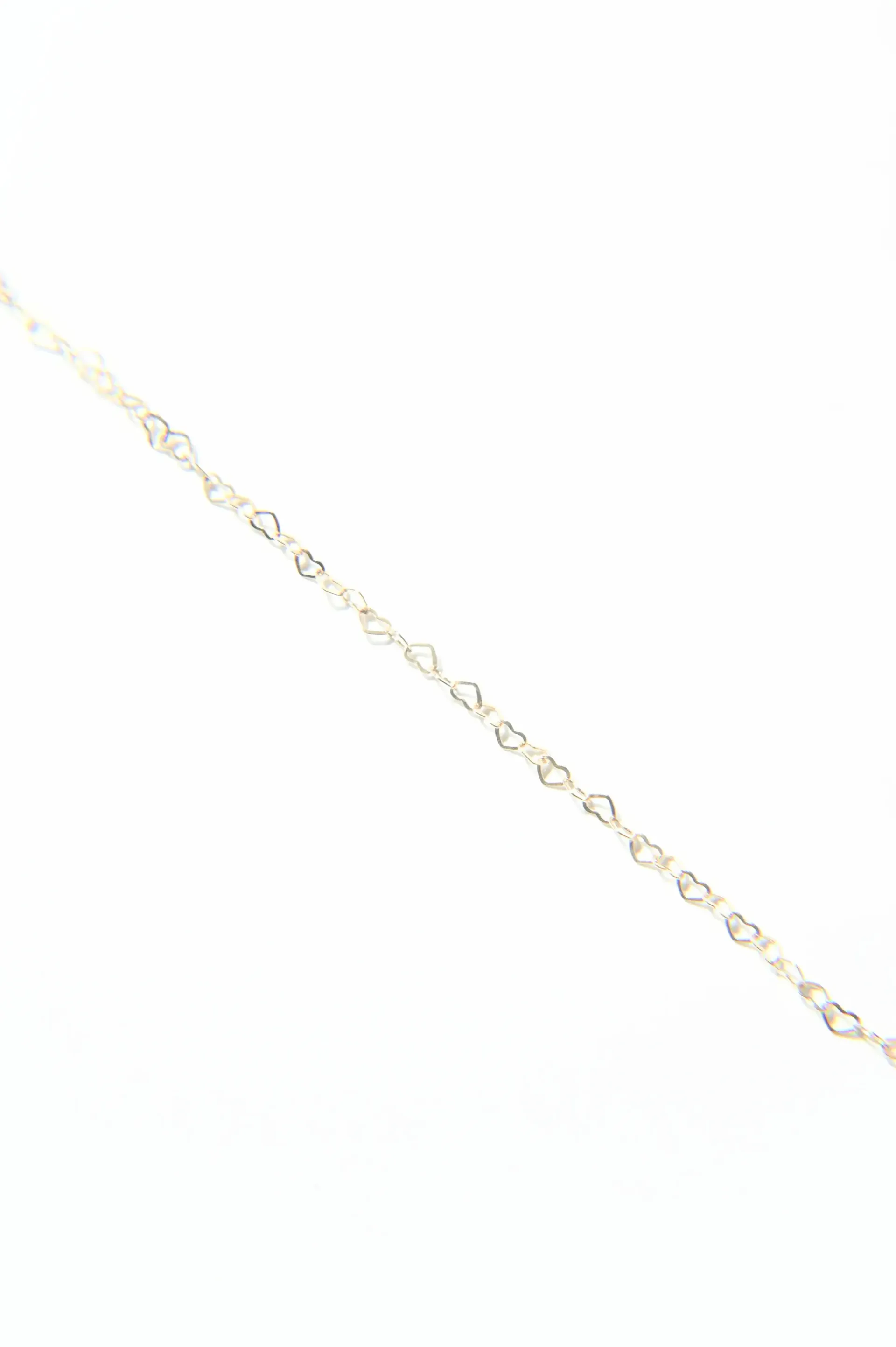 A close up of a gold chain on a white background.