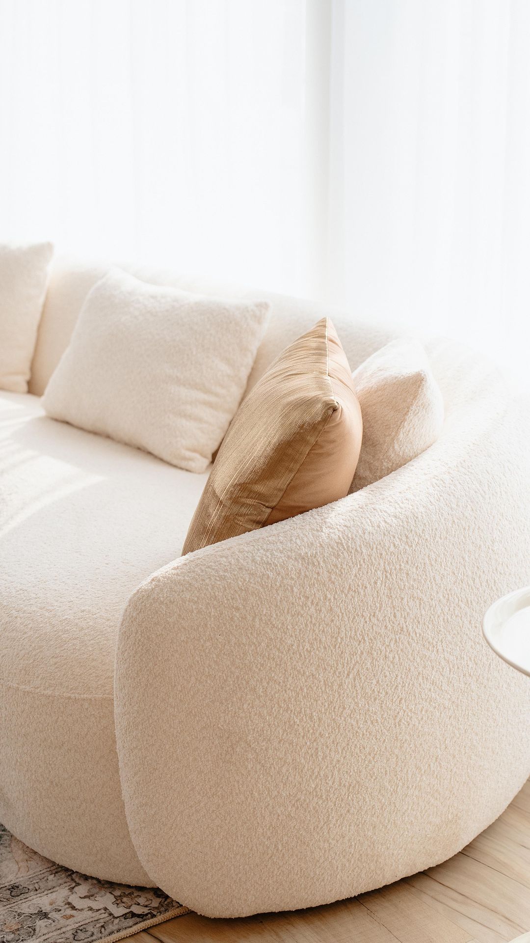 A white couch is sitting in a living room next to a window.