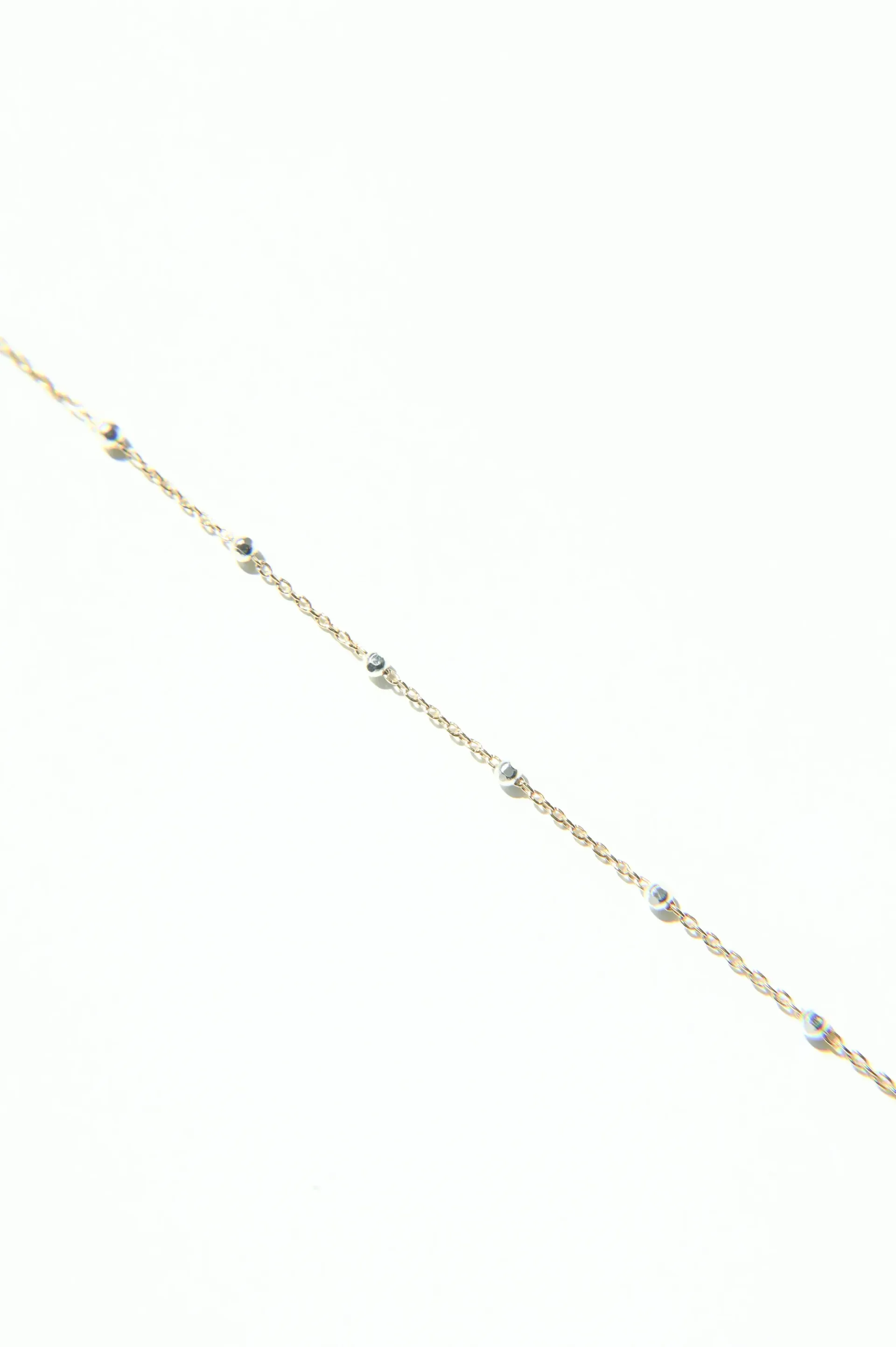 A gold chain with diamonds on it on a white background.