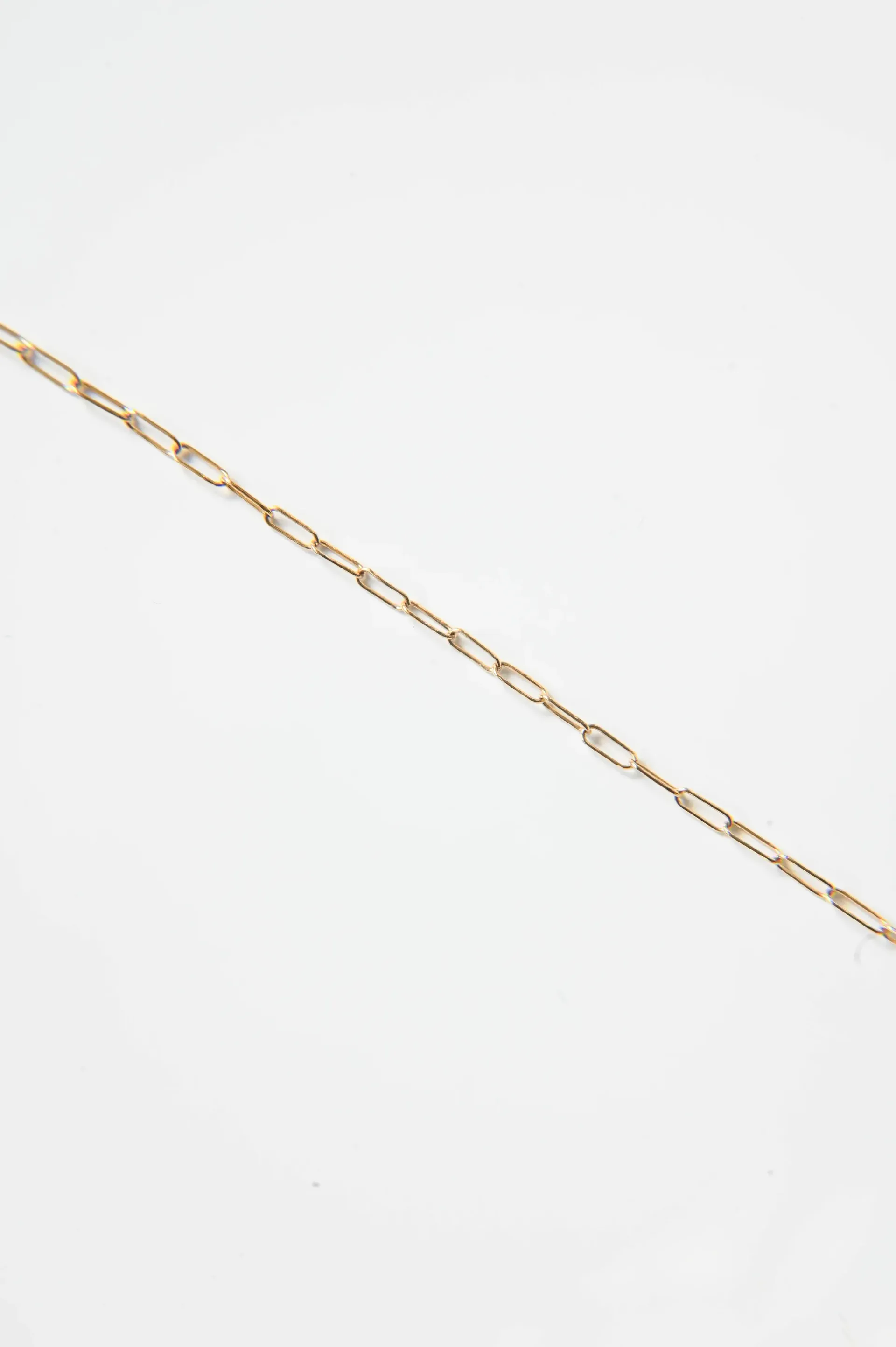 A close up of a gold chain on a white background.