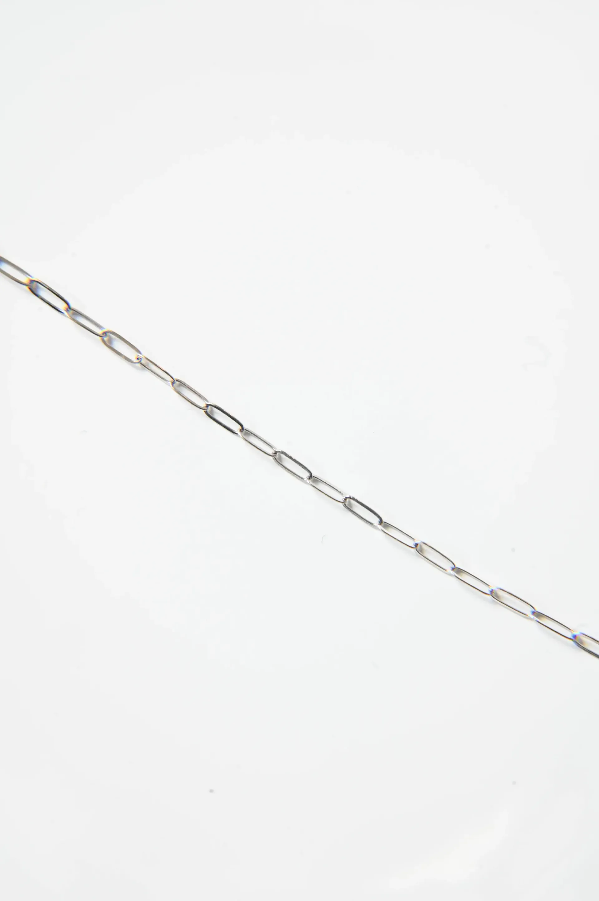 A close up of a silver chain on a white background.