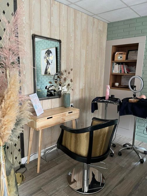 Un salon de coiffure avec une chaise, un miroir et une table.