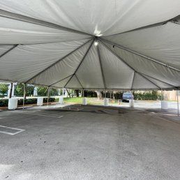 View from inside a large, white tent set up in a parking lot.