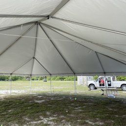 Inside of a large white tent with a truck parked outside on grass.