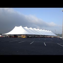 Large white tent set up in a parking lot under a cloudy sky.