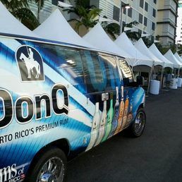 Dona Q Puerto Rican rum van parked in front of white tents, advertising a promotional event outdoors.