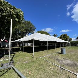 A large white tent set up on a green lawn under a clear blue sky.
