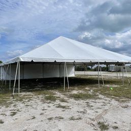 Large white tent set up outdoors, possibly for an event. Cloudy sky and grassy ground.
