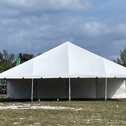 White tent set up on grass under a cloudy sky, possibly for an outdoor event.