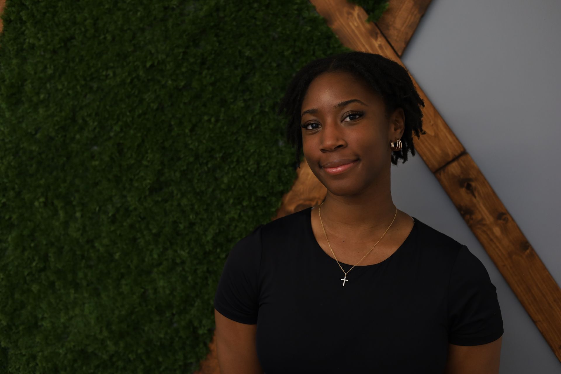 Femme à lunettes, bras croisés, souriante. Vêtue d'un haut noir et d'un jean, elle se détache sur un fond bleu.