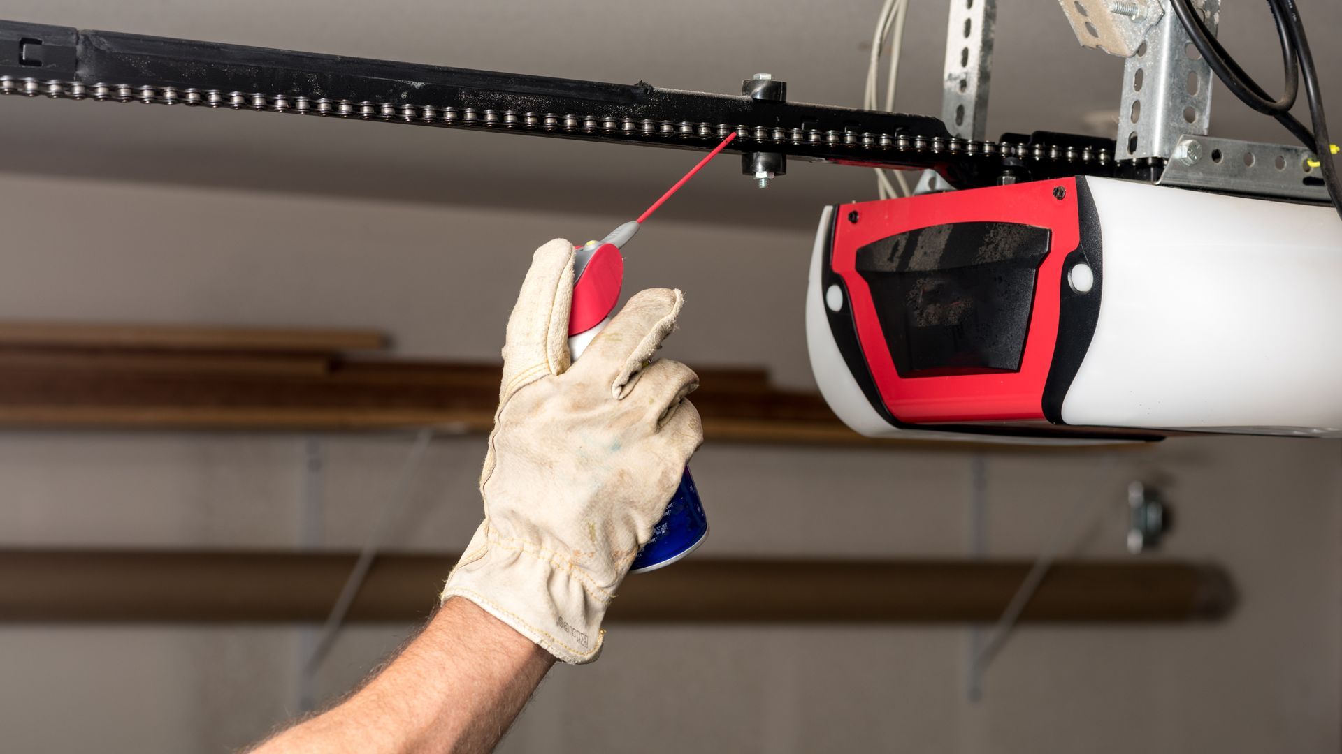 Applying oil to a chain of a garage door opener.