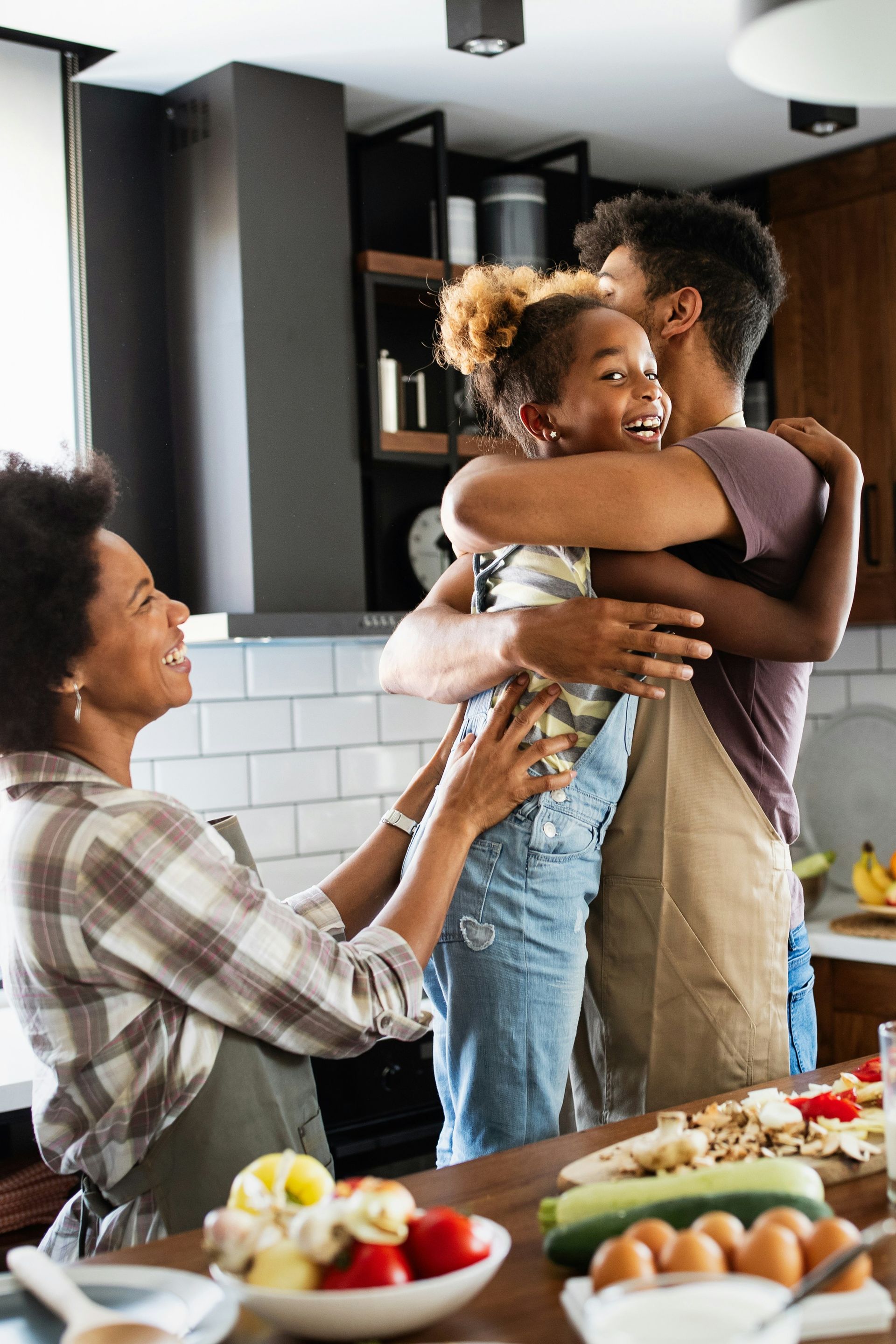 A family is hugging each other in a kitchen.