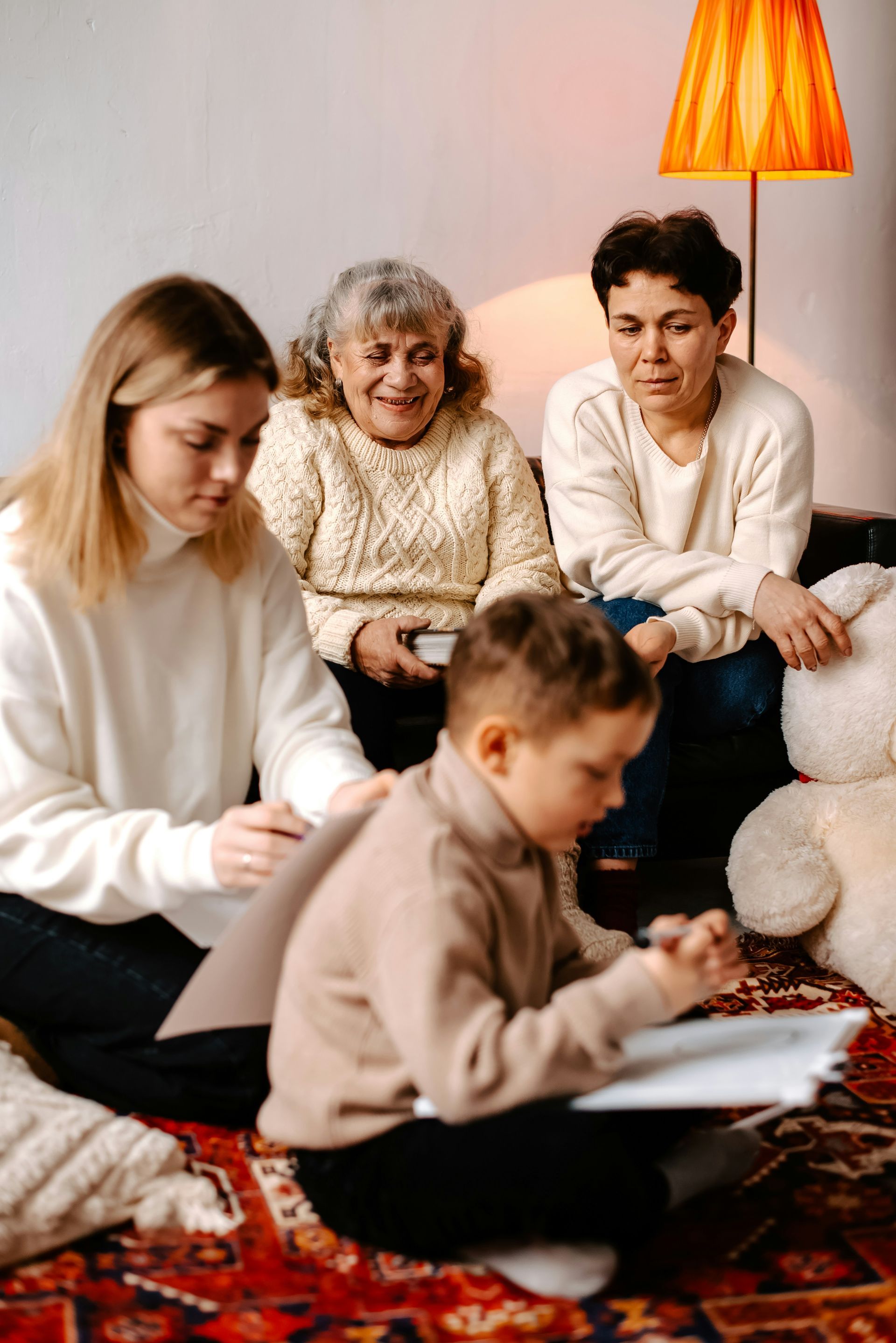 A family is sitting on the floor reading a book together.