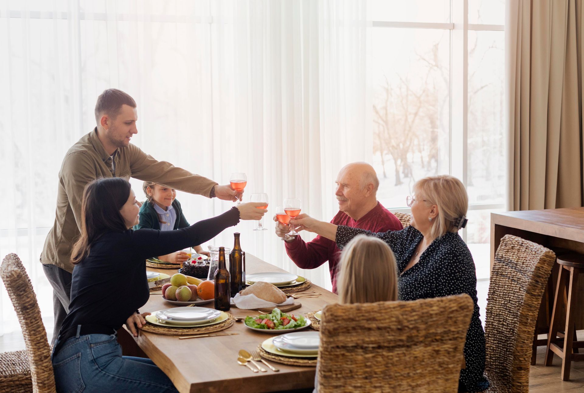 A family is sitting at a table toasting with wine glasses.