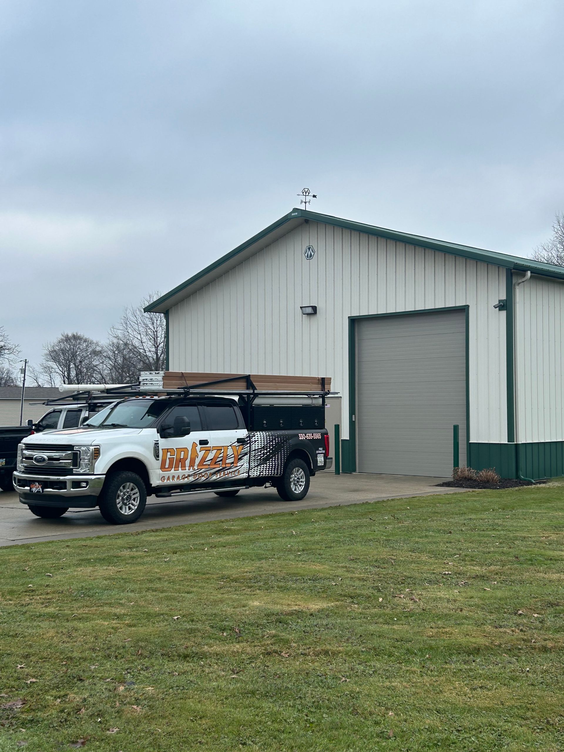 White pickup truck with company logo parked outside a white warehouse with a closed gray garage door.