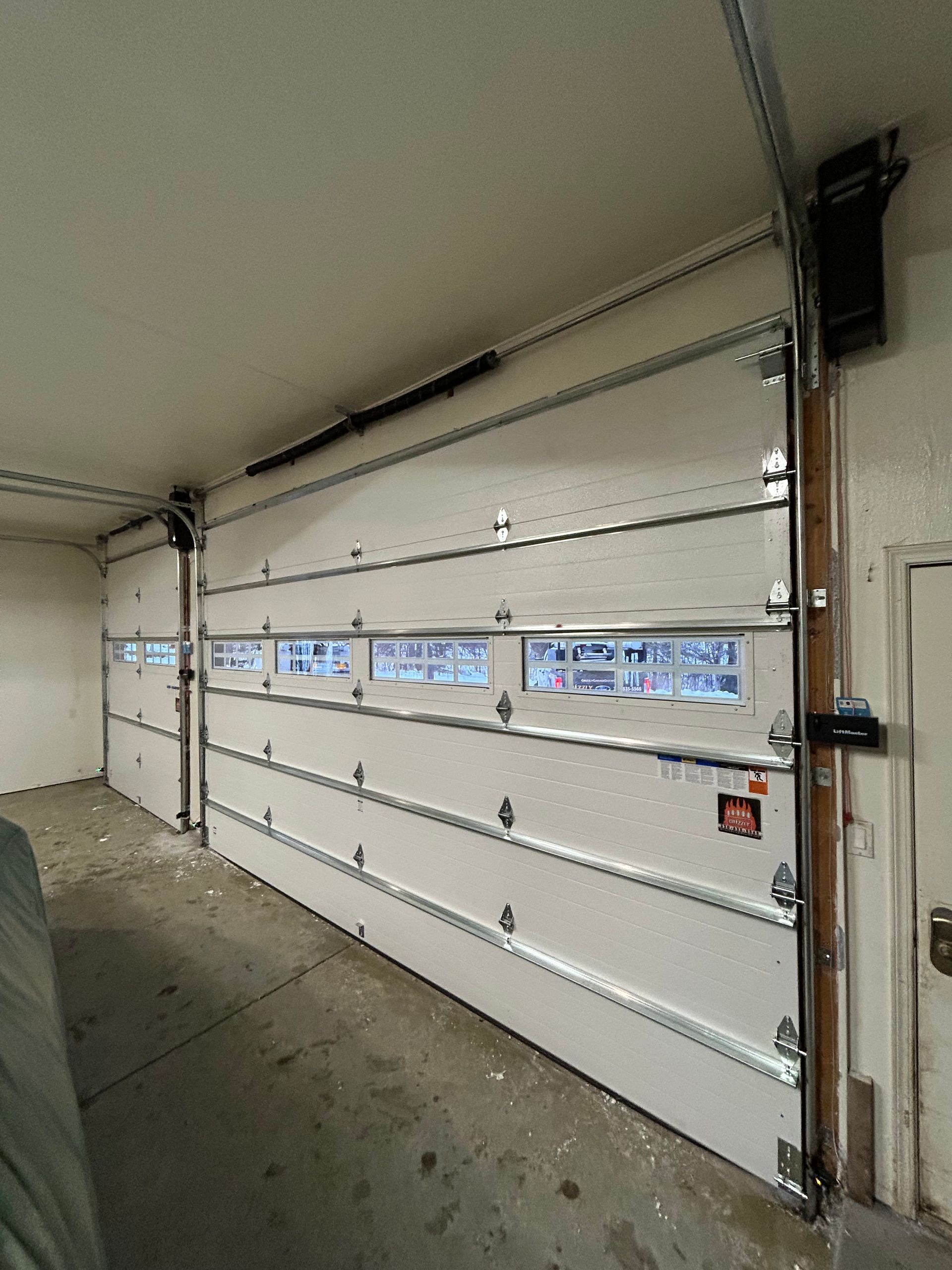 White sectional garage door with windows, inside a garage.