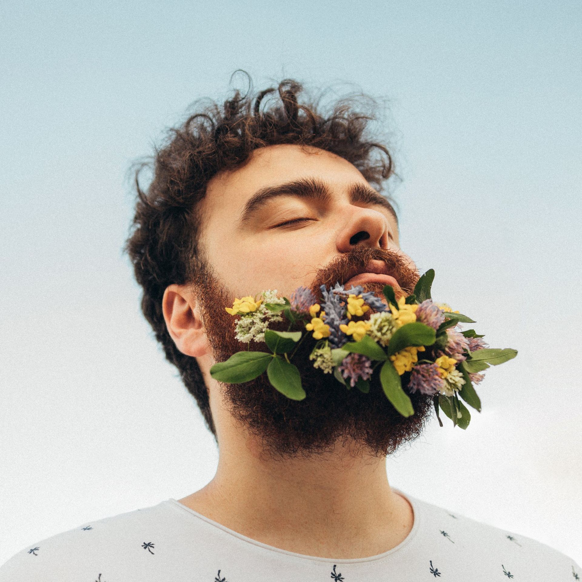 A man with a beard has flowers in his mouth