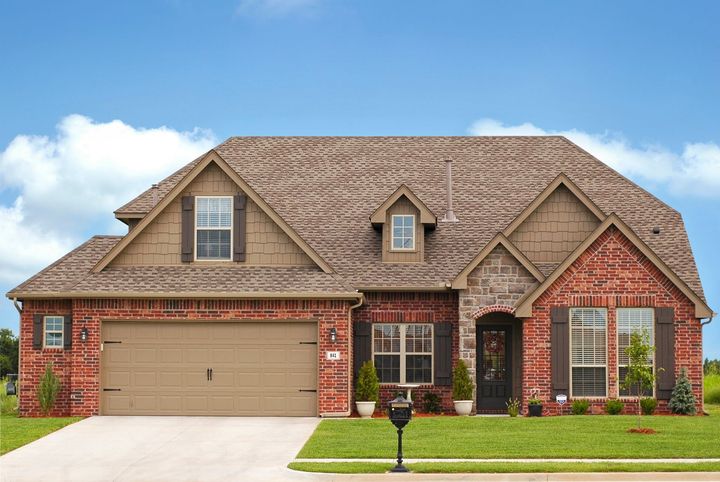 Une grande maison en briques avec une porte de garage beige