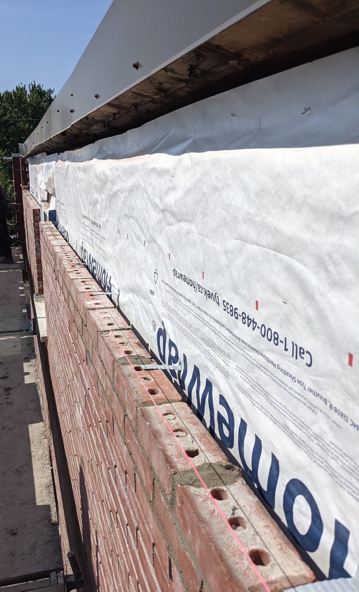 Un mur de briques est recouvert d'une bâche blanche.