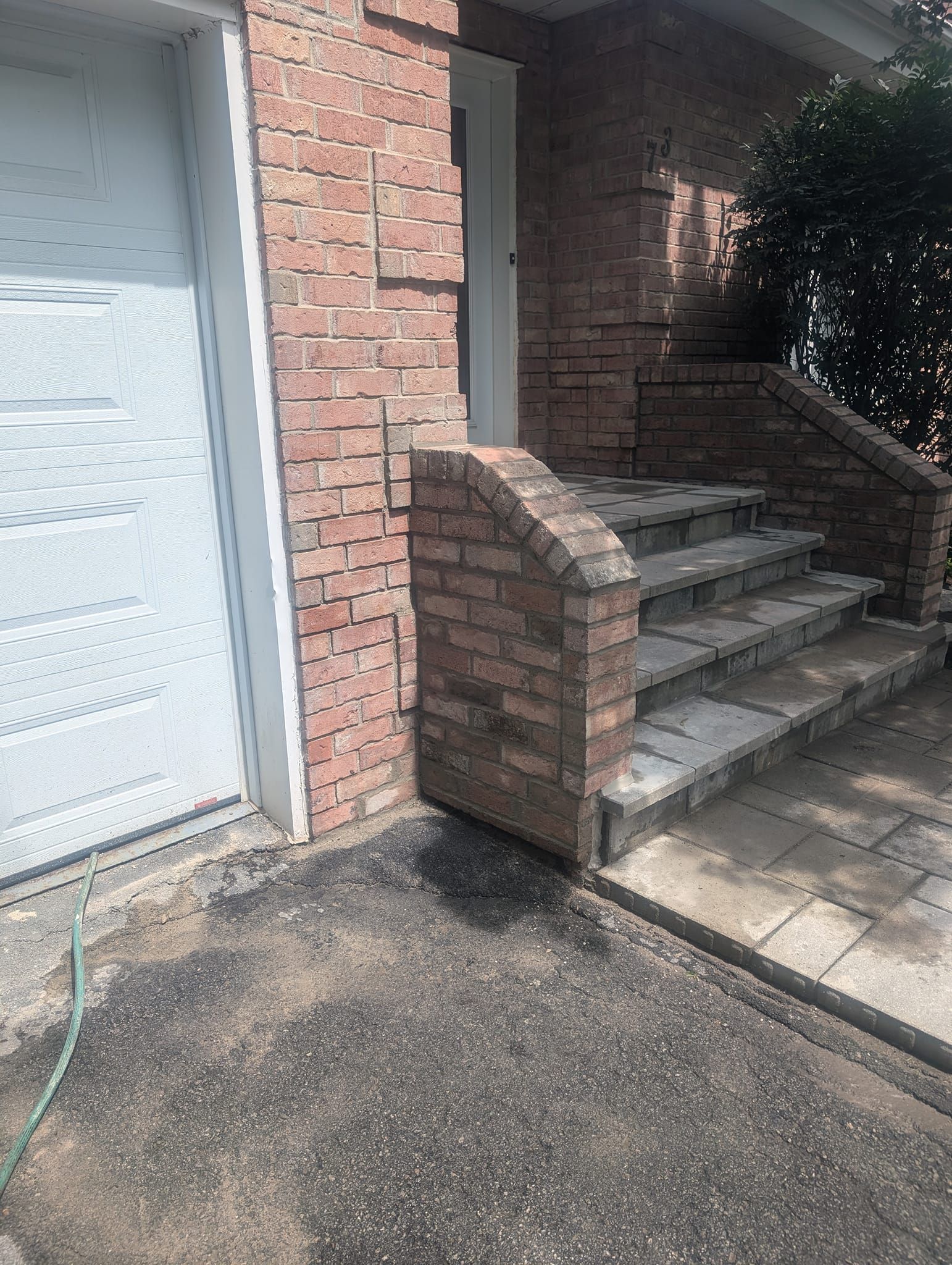 Un bâtiment en briques avec des escaliers qui y mènent et une porte de garage blanche.