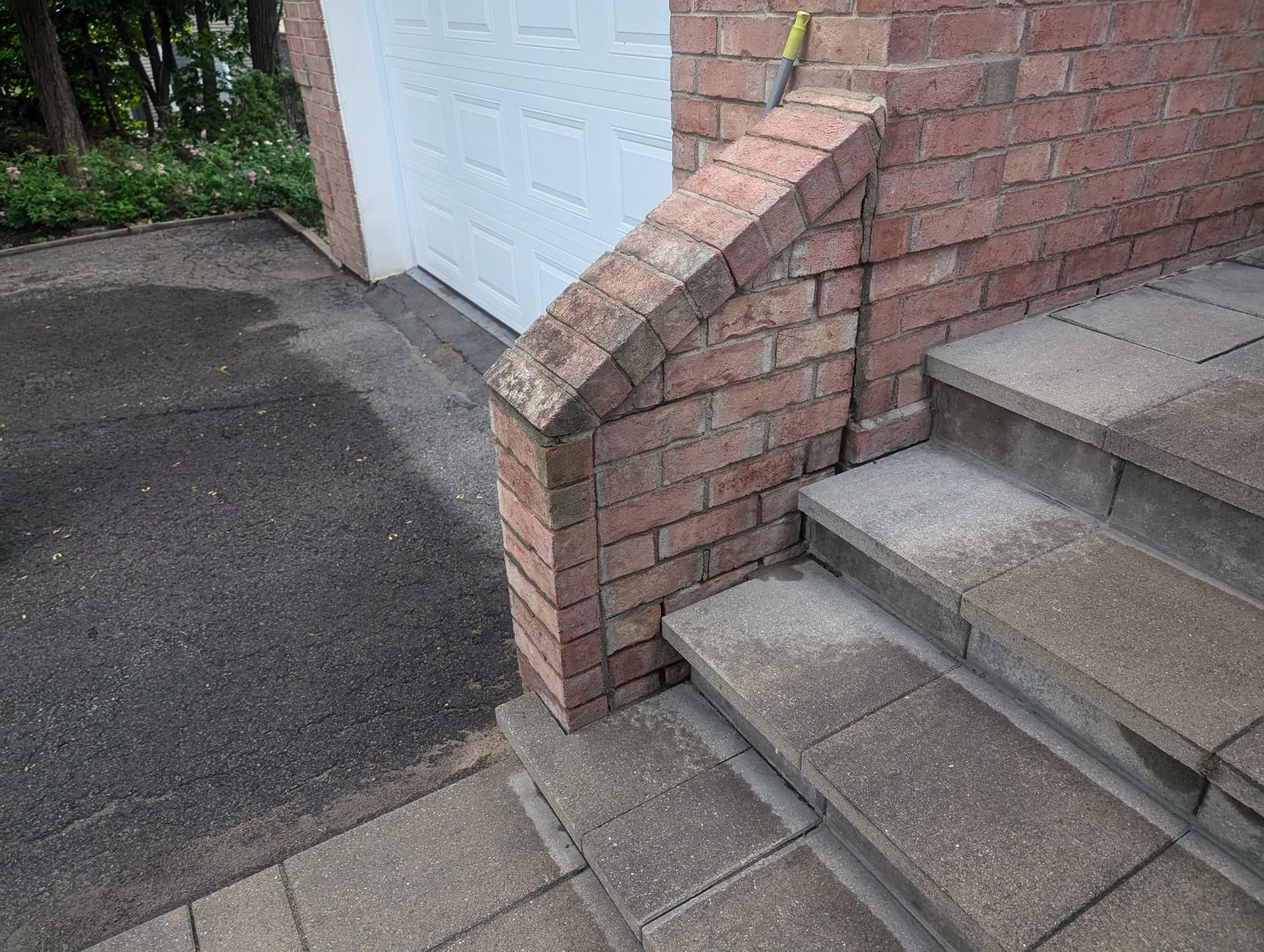 Un mur de briques à côté d'un escalier et d'une porte de garage.