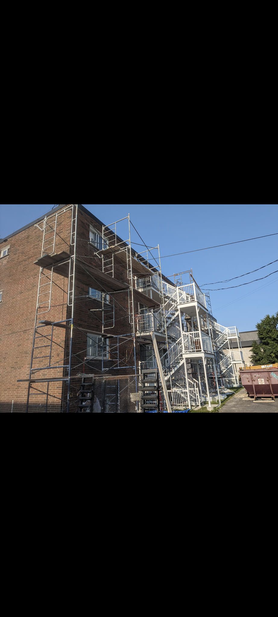 Un grand bâtiment en briques avec un escalier de secours sur le côté.