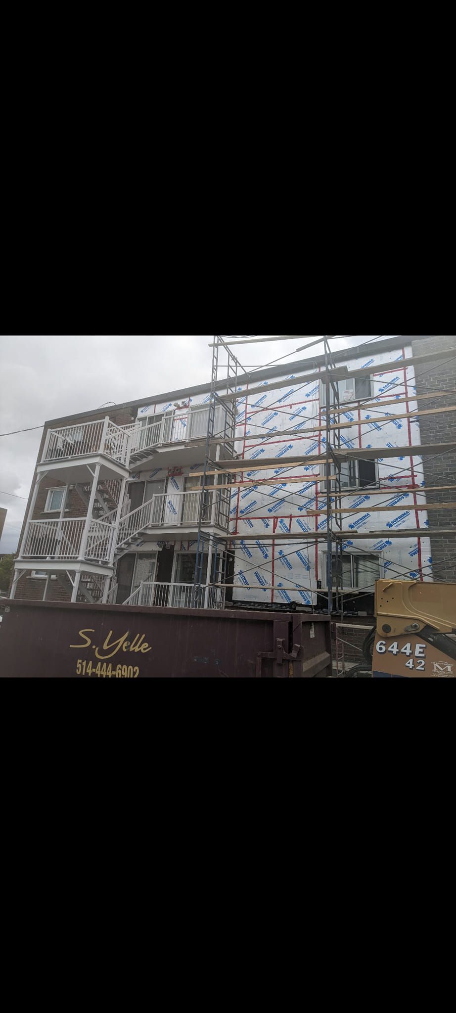 Un bâtiment est en cours de construction avec un échafaudage sur le côté.