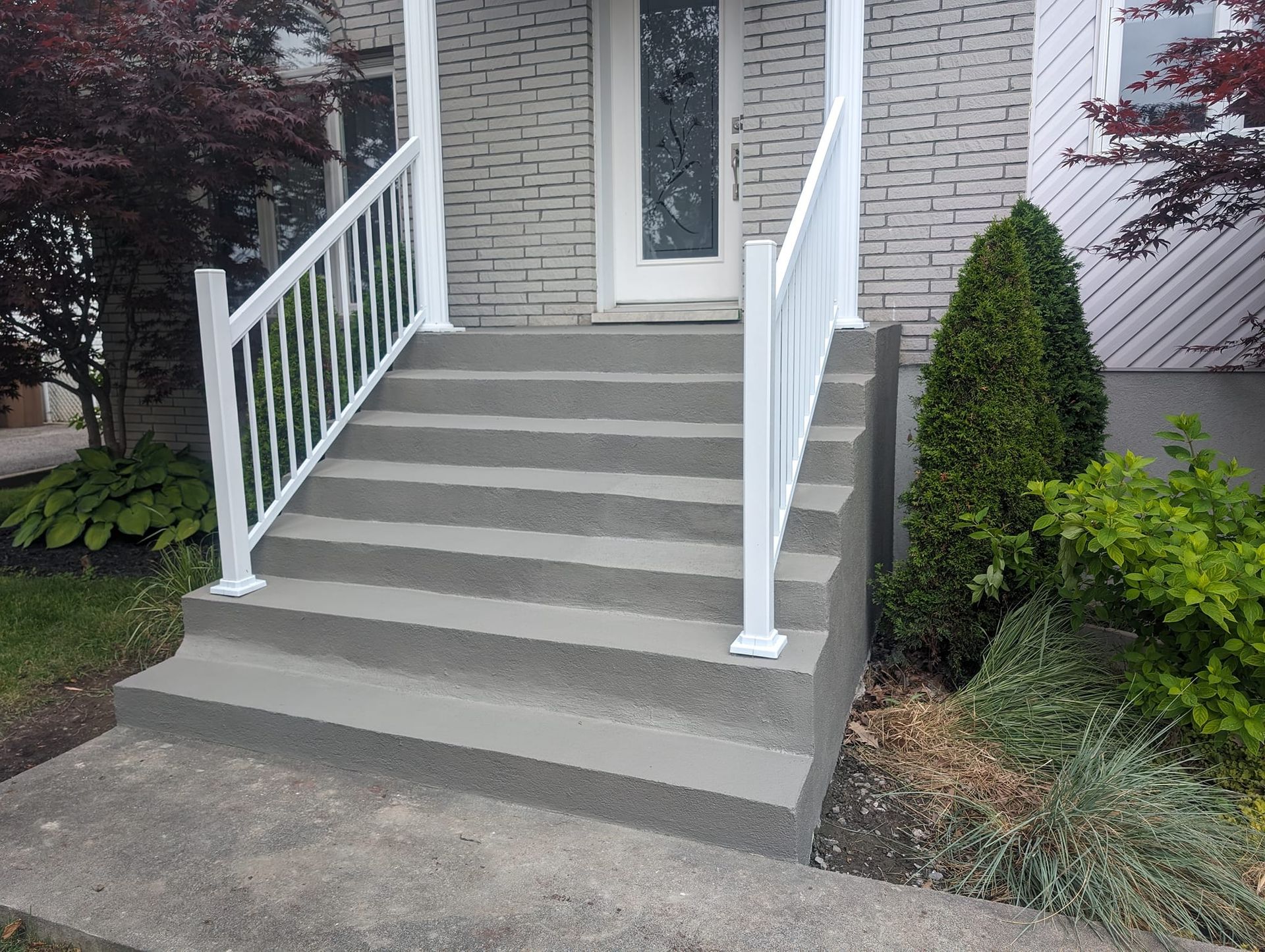 Un ensemble d'escaliers menant à la porte d'entrée d'une maison avec une balustrade blanche.