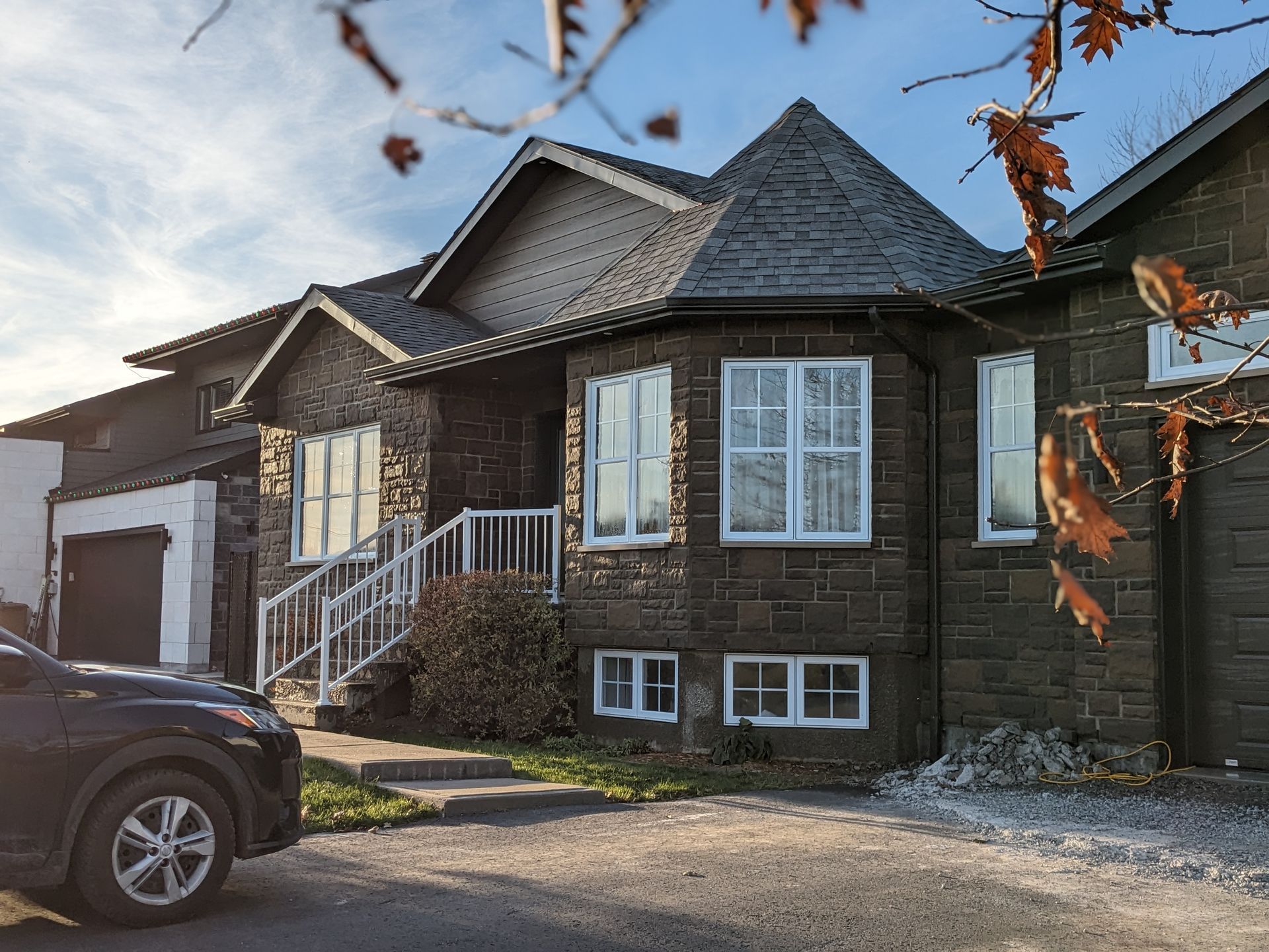 Une voiture est garée devant une grande maison en briques.