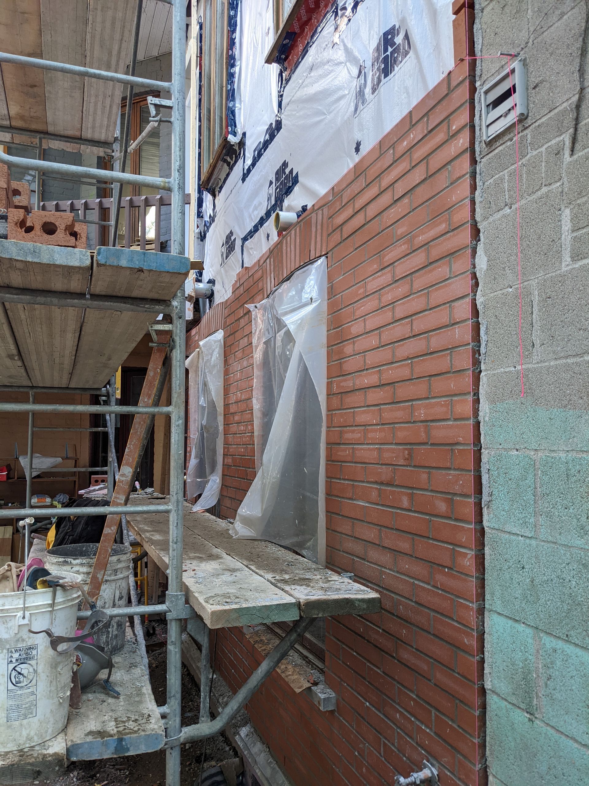 Un mur de briques est en train d'être construit sur le côté d'un bâtiment.