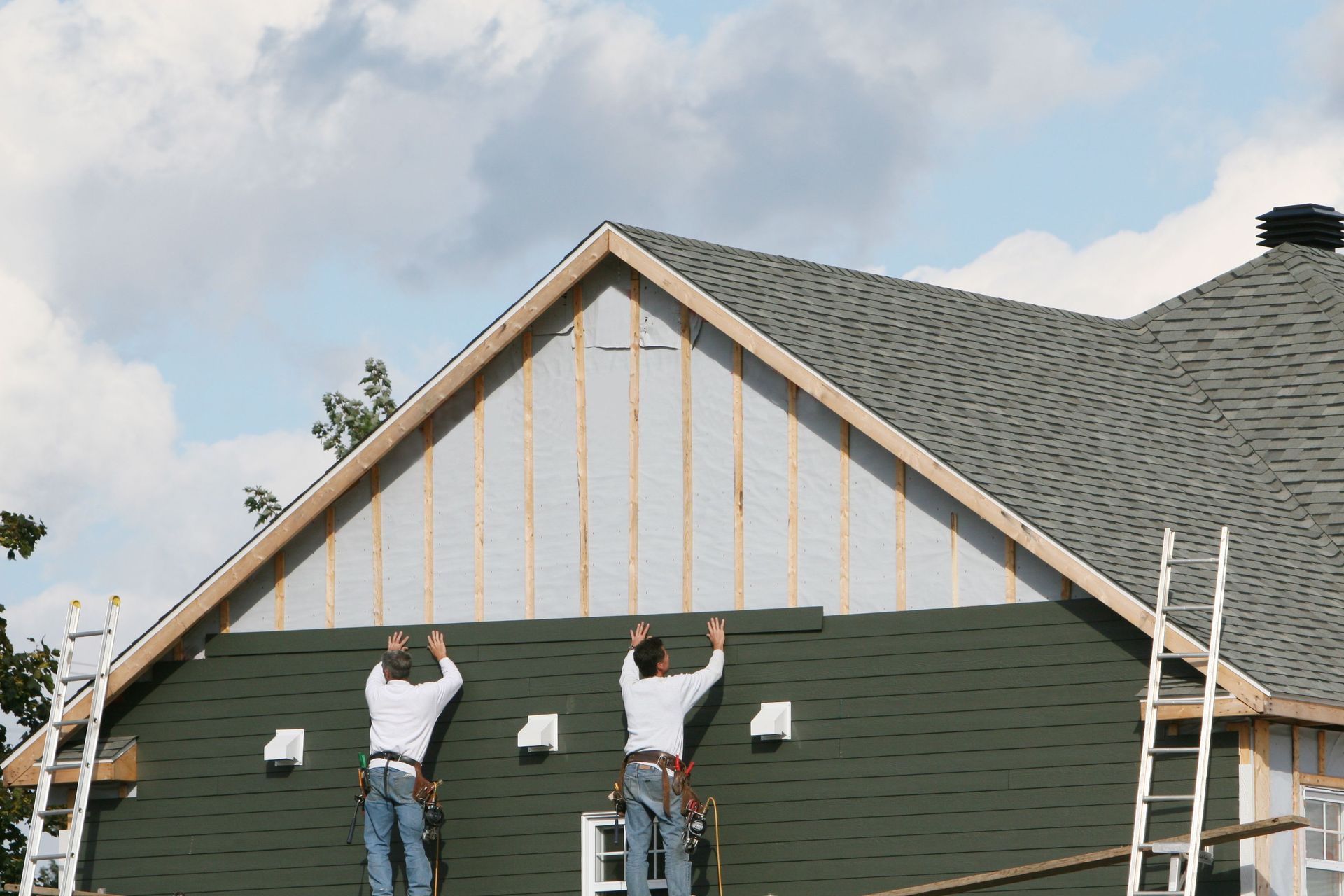 Two men are working on the side of a house — Overland Park, KS — Johnson County Solutions