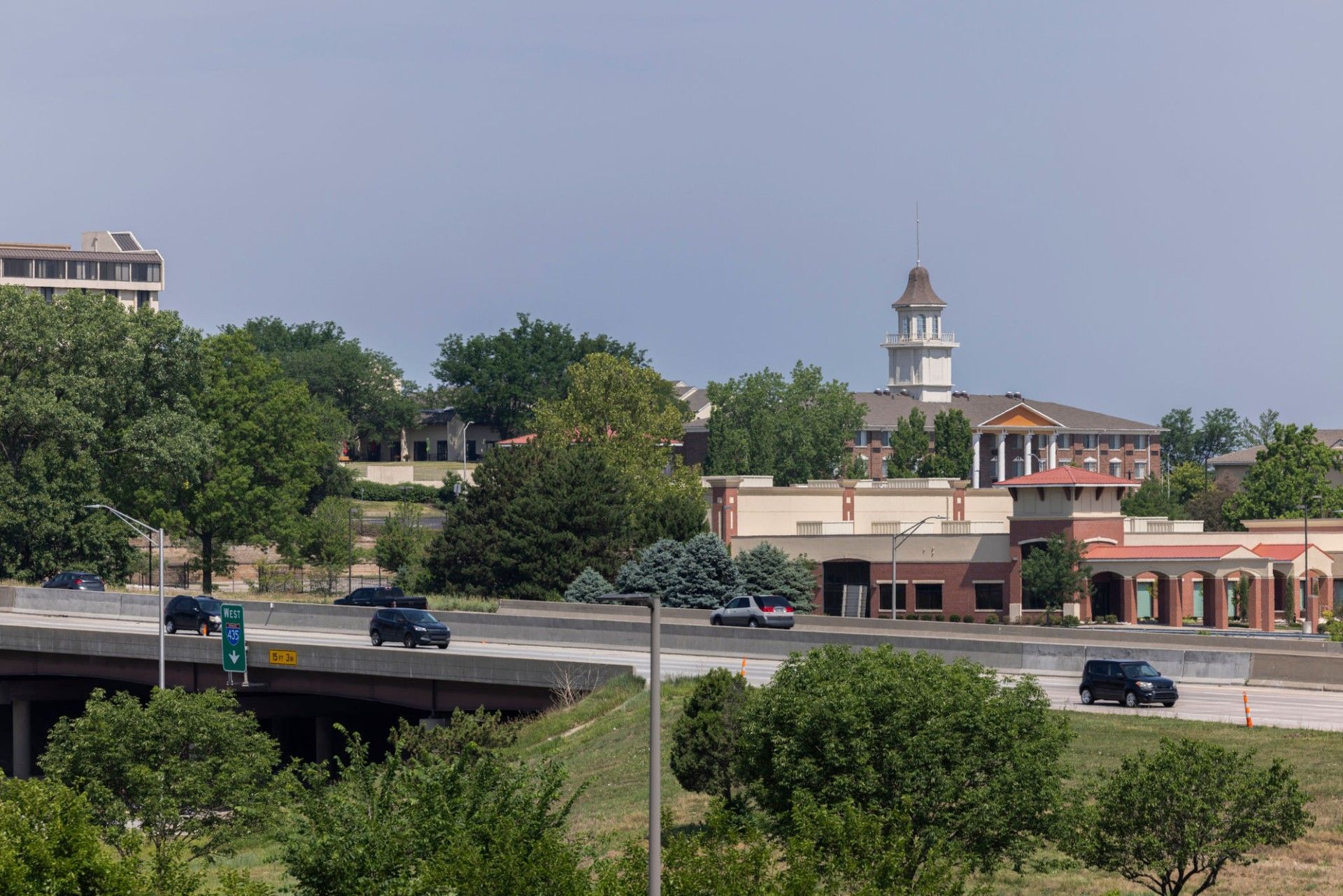 A bridge over a highway with a building in the background — Overland Park, KS — Johnson County Solutions