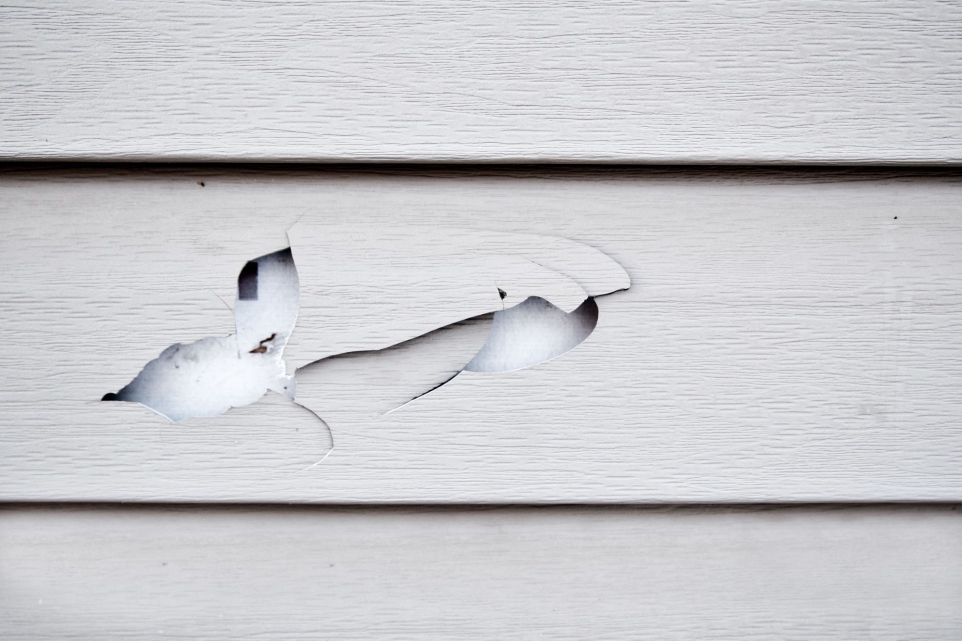 A close up of a white siding with a hole in it — Overland Park, KS — Johnson County Solutions