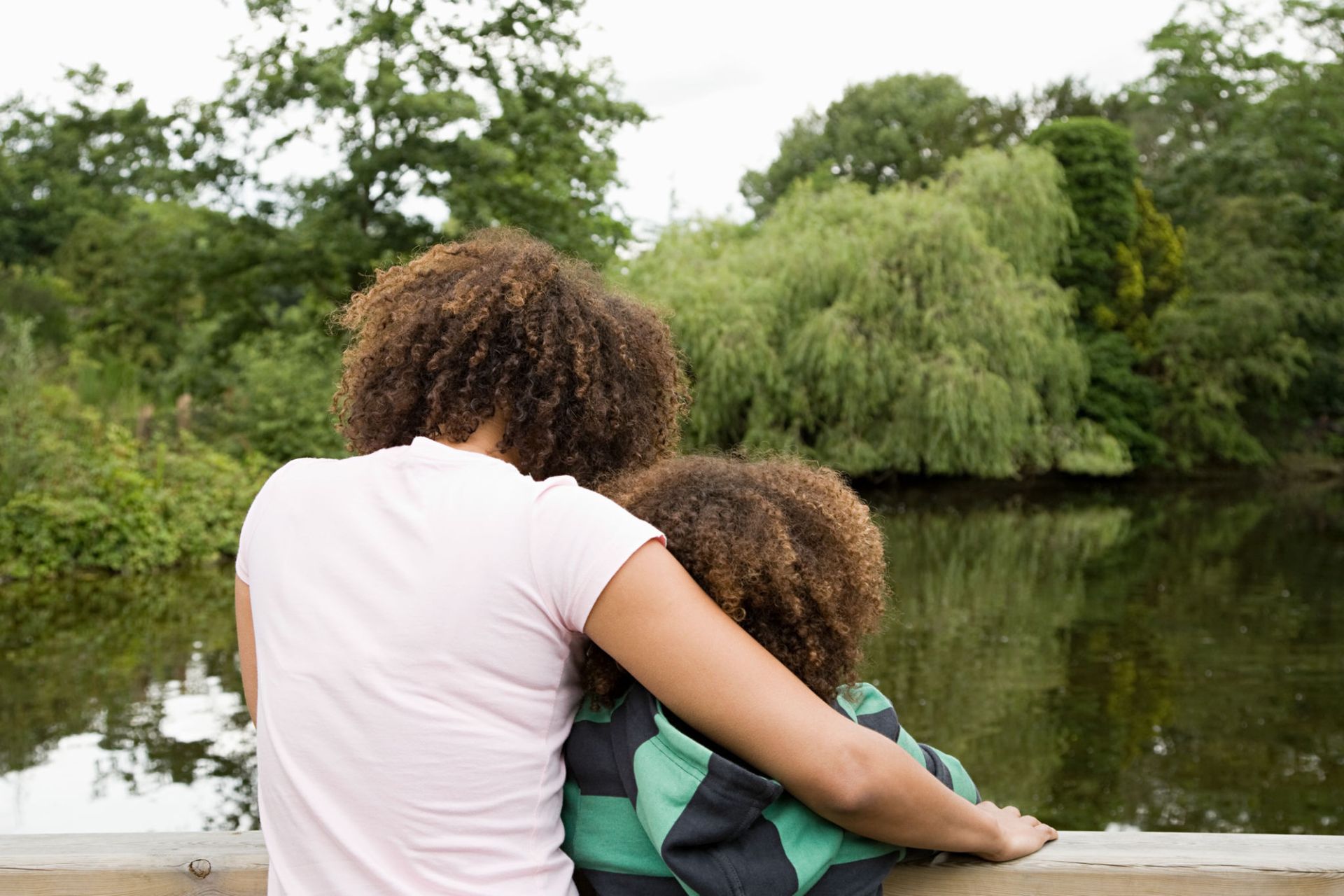 Two women are sitting on a bridge overlooking a lake — Overland Park, KS — Johnson County Solutions
